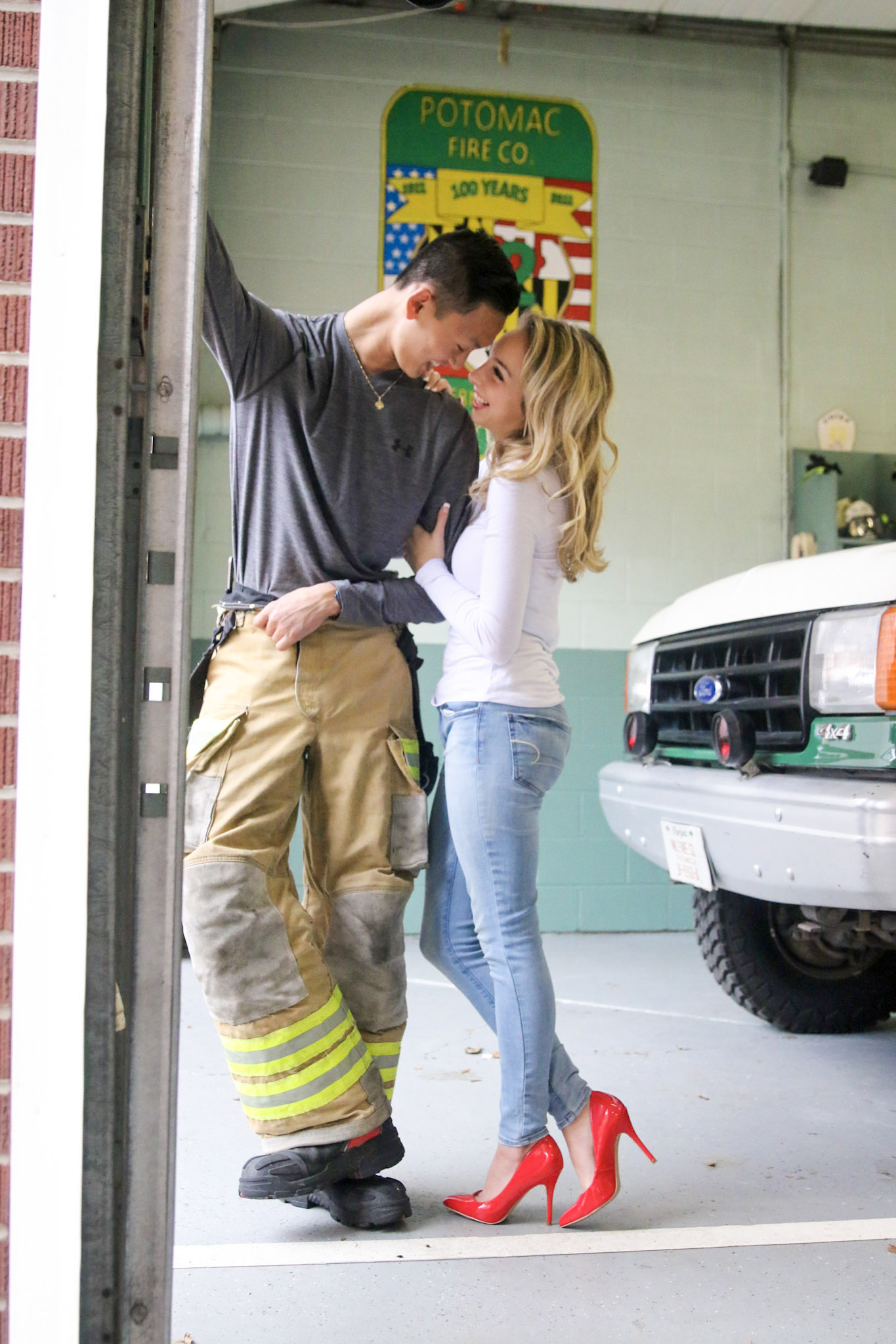 the young woman clasped her arms around his man's arm, both of them smiling pleasantly. The man leans in slightly nearer her.