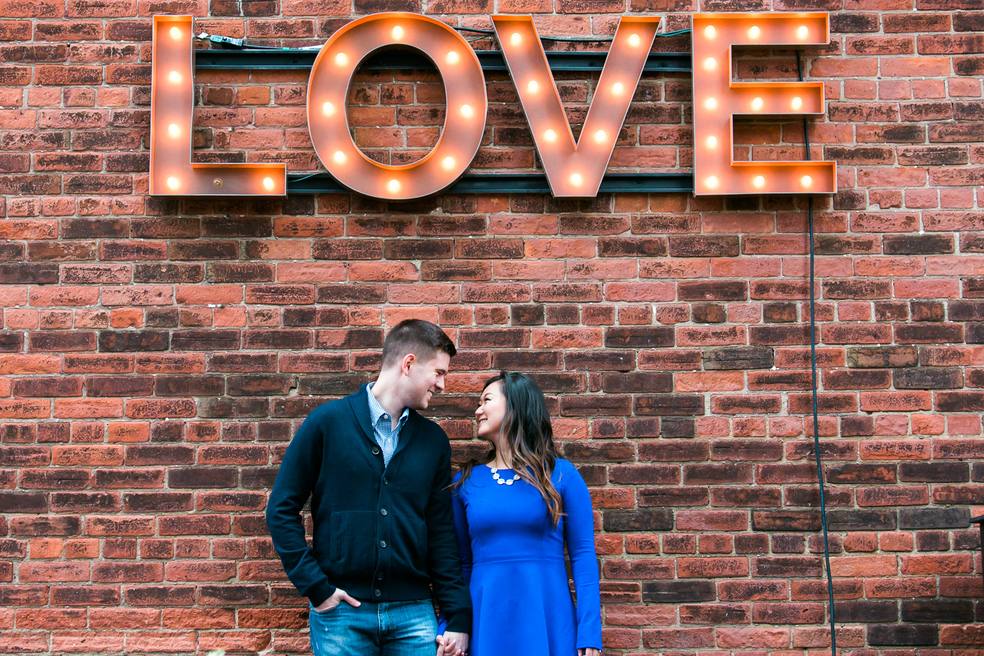 the couple looking at each other lovingly with a love signage on top of them.