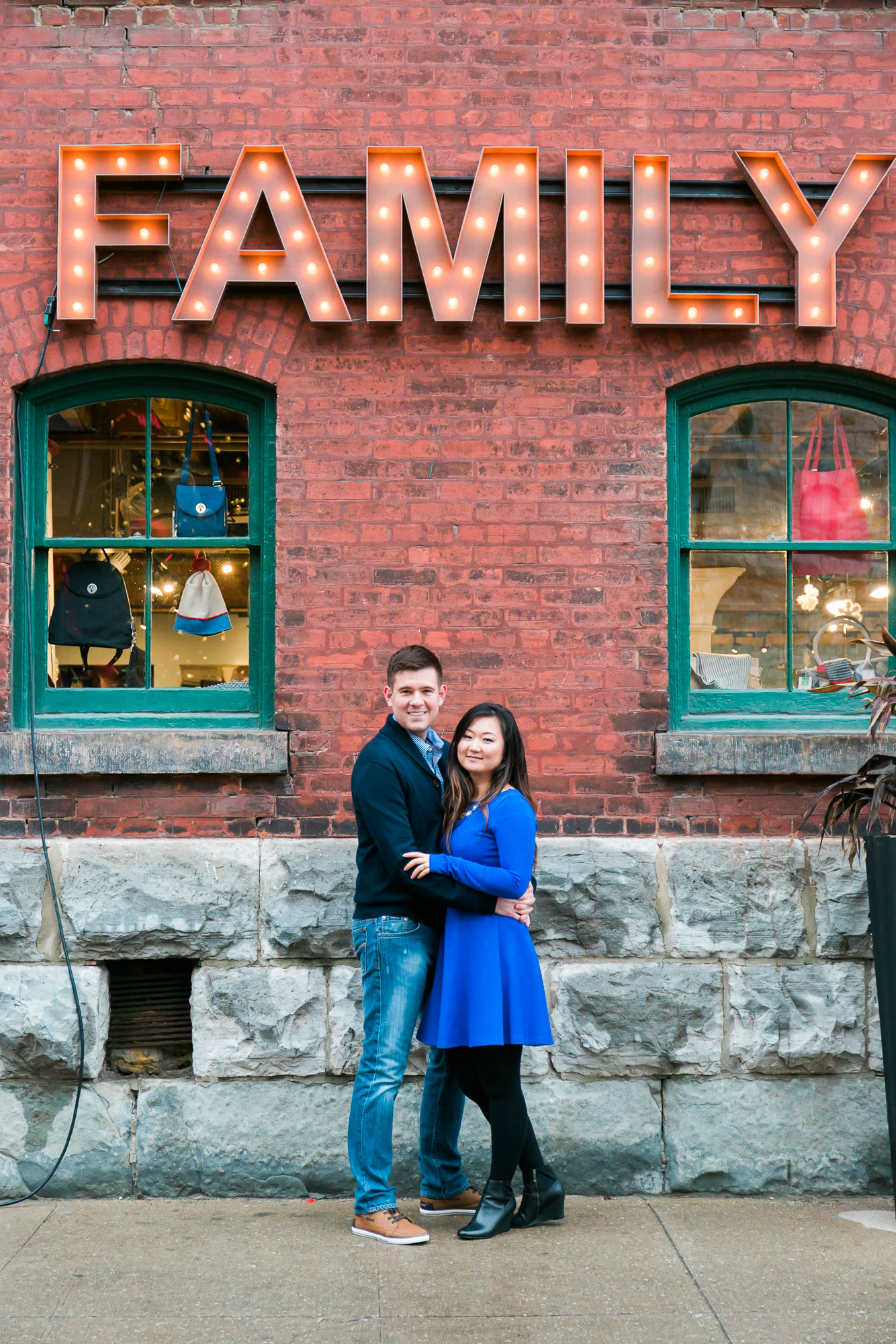 The pair are beaming with joy while embracing, and there is a family display positioned above them.