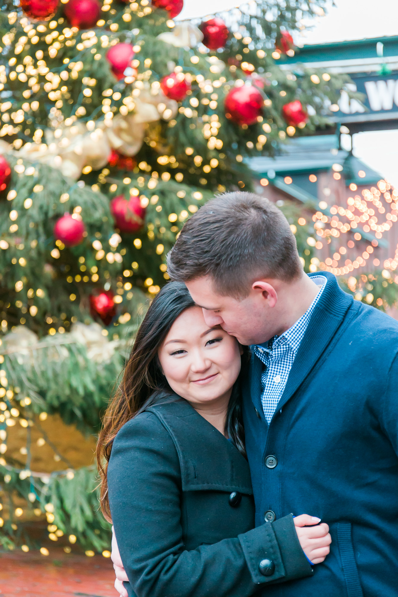 Nick is placing a gentle kiss on Esther's forehead as she embraces him. The pair are both dressed in navy blue coats.