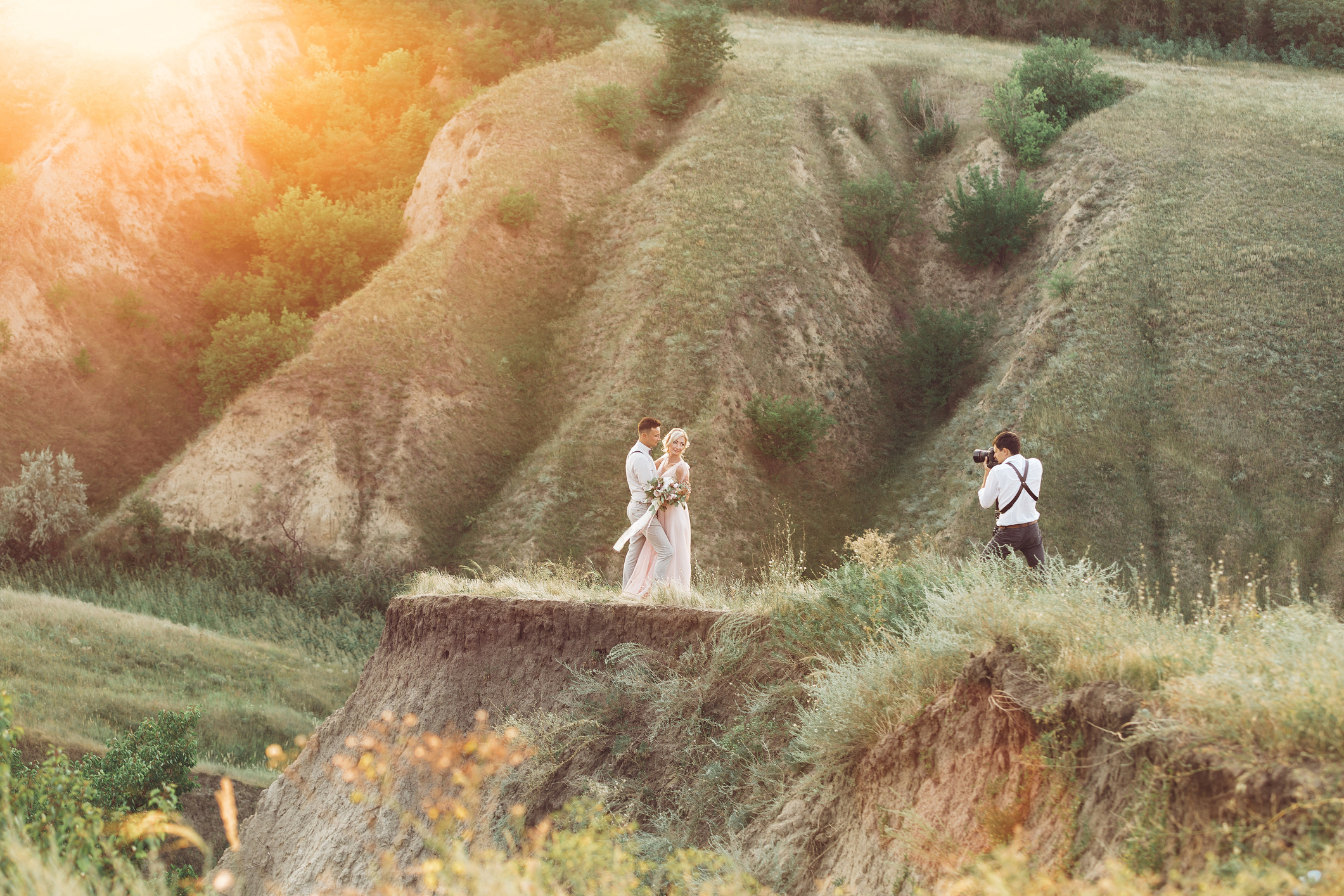 wedding photographer takes pictures of bride and groom in nature. wedding couple on photo shoot. photographer in action