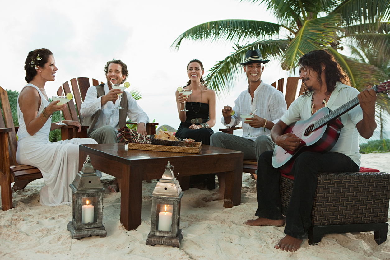 While the bride and groom and their friends enjoy the event while sipping cocktails, a guy plays guitar. 