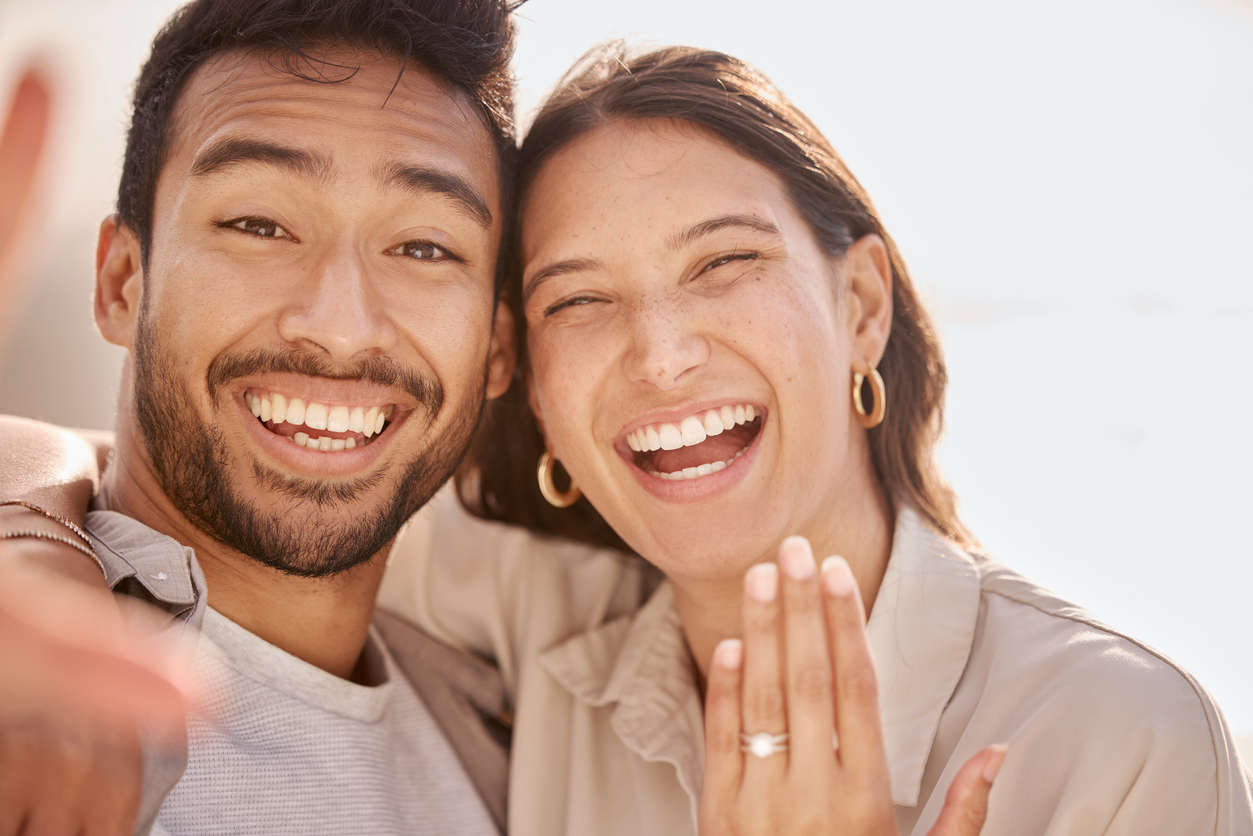 shot of a young couple showing a ring after getting engaged at the beach