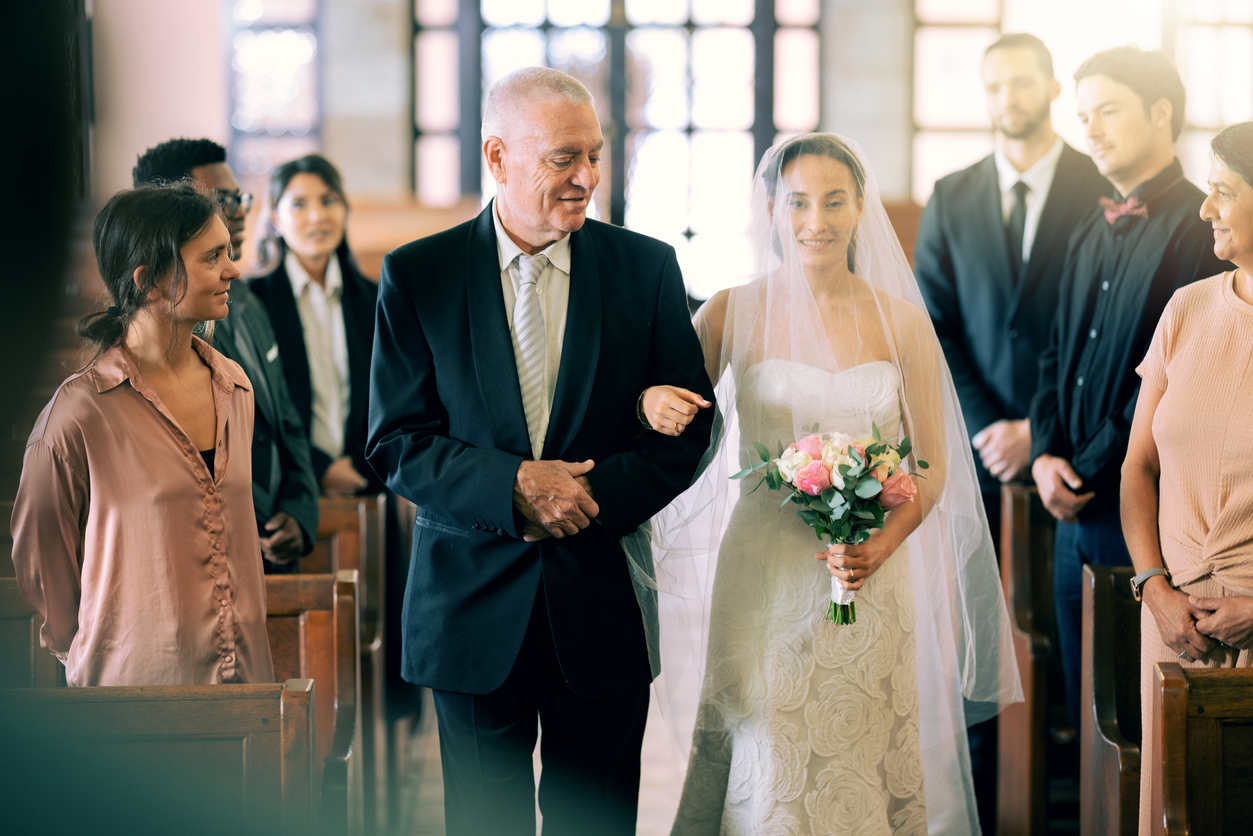 with a smile, the father walks down her daughter down the aisle.