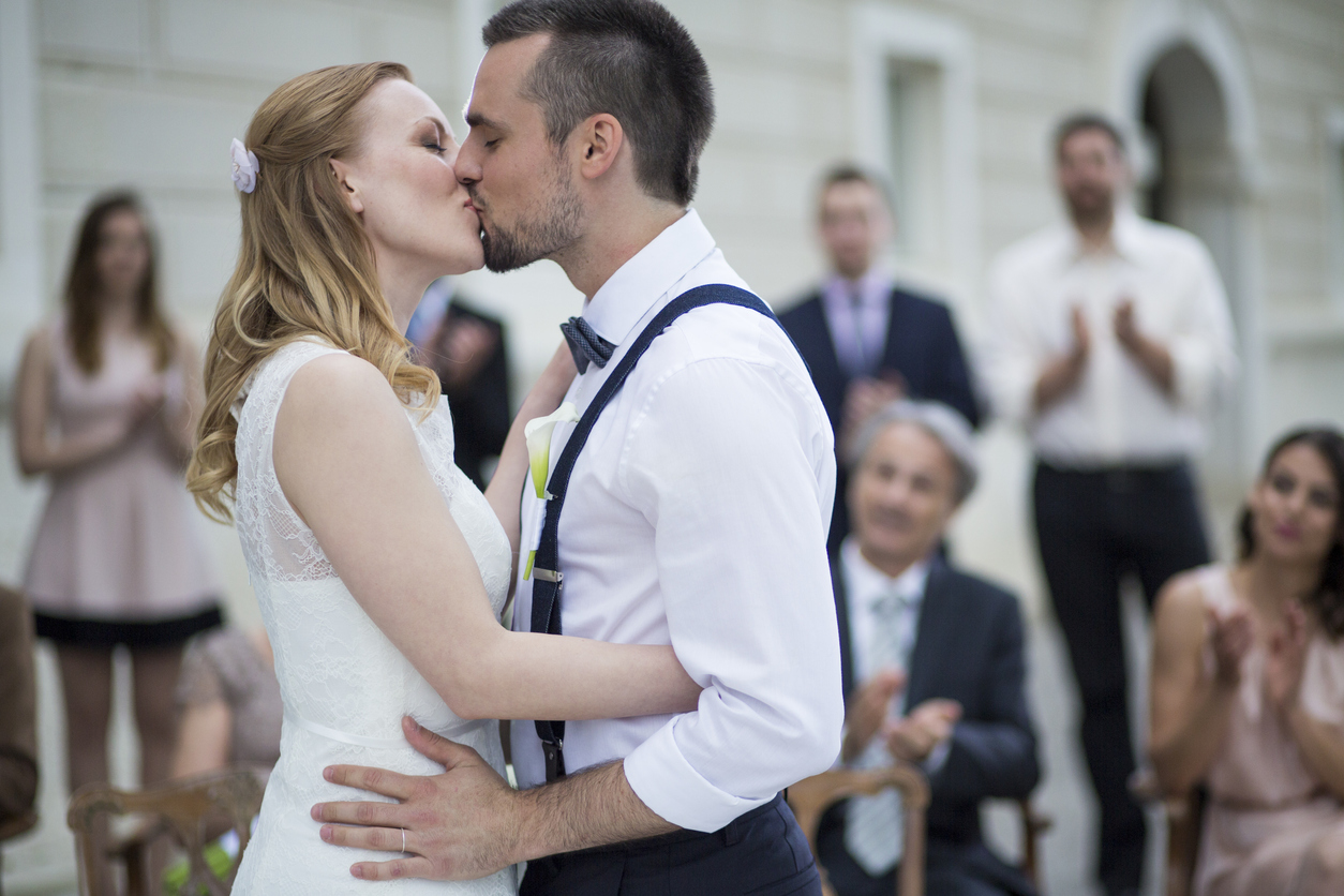 Wedding ceremony ending with couple kissing and guests applauding.