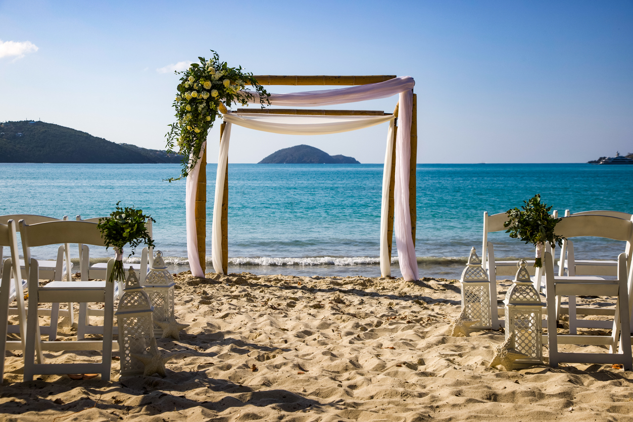 A bouquet of flowers rest on a wedding gazebo near the water’s edge before a wedding ceremony with a bay of water and an island in the background