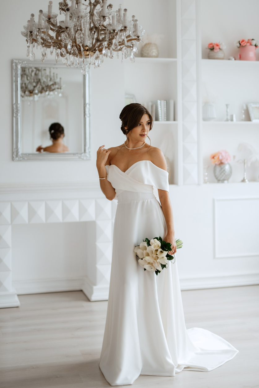 the brunette bride wears a long silky white wedding gown and clutches a modest bridal bouquet.