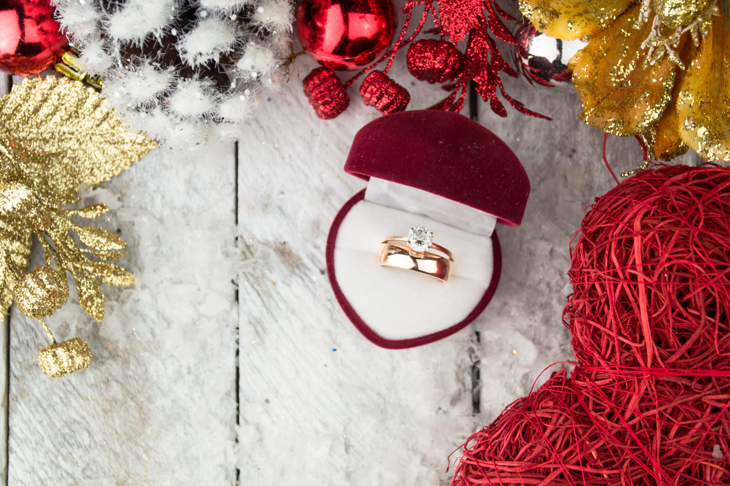 Wedding ring among Christmas decorations on wood background.