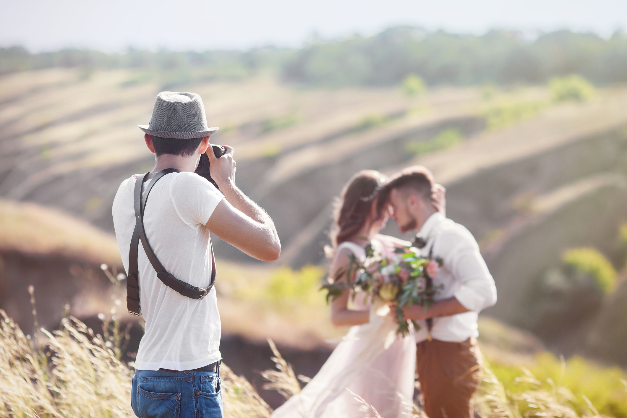 a wedding photographer takes pictures of the bride and groom in nature, the photographer in action