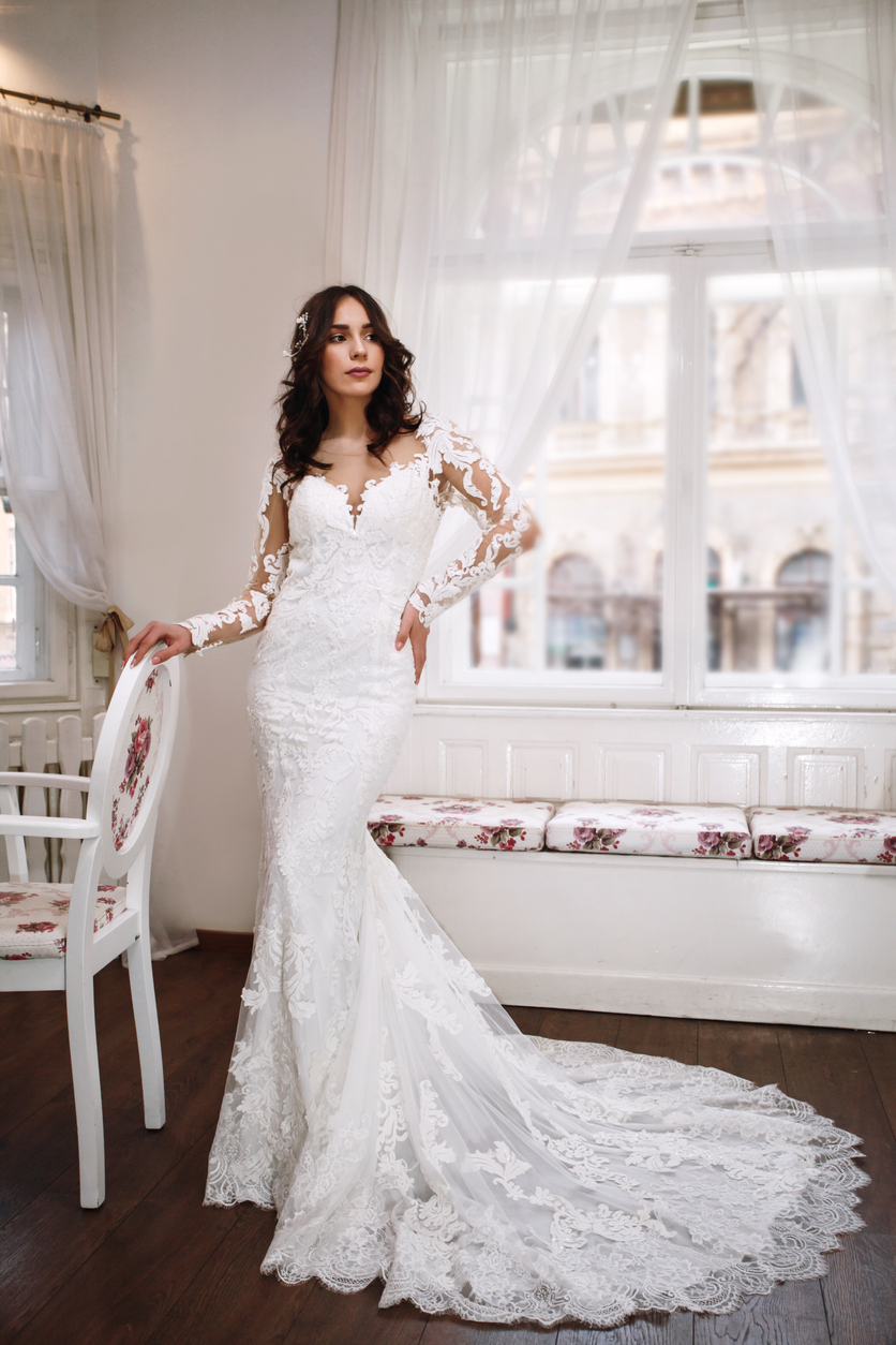 gorgeous bride in her long lacey bridal gown .