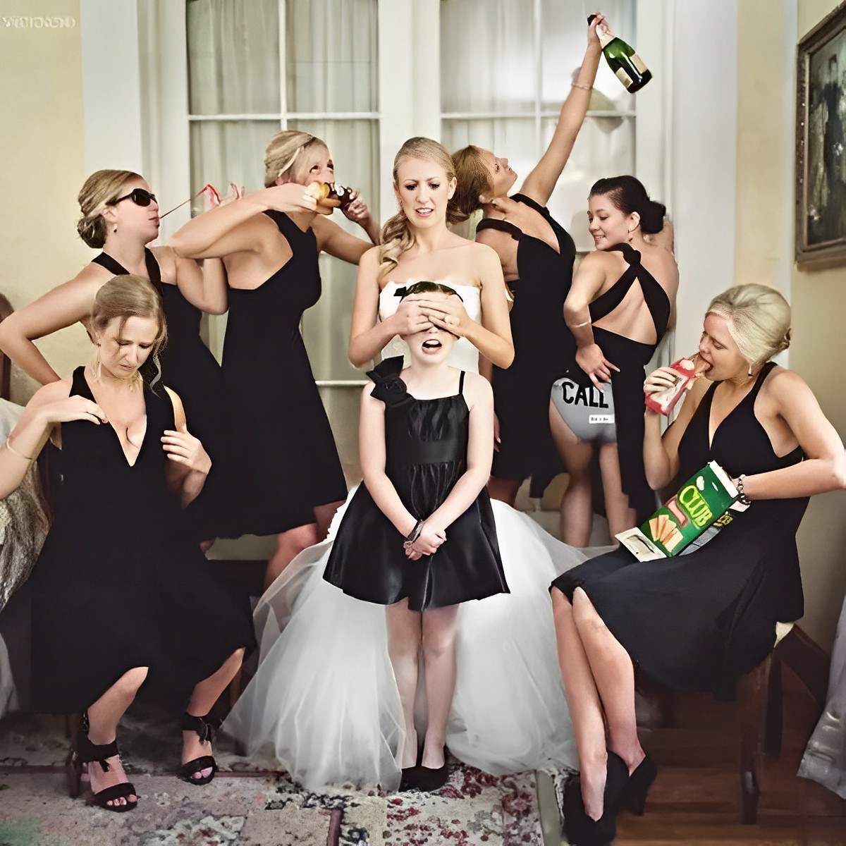 The bride closes the flower girl's eyes as the bridesmaids make crazy and fun poses in the rear.