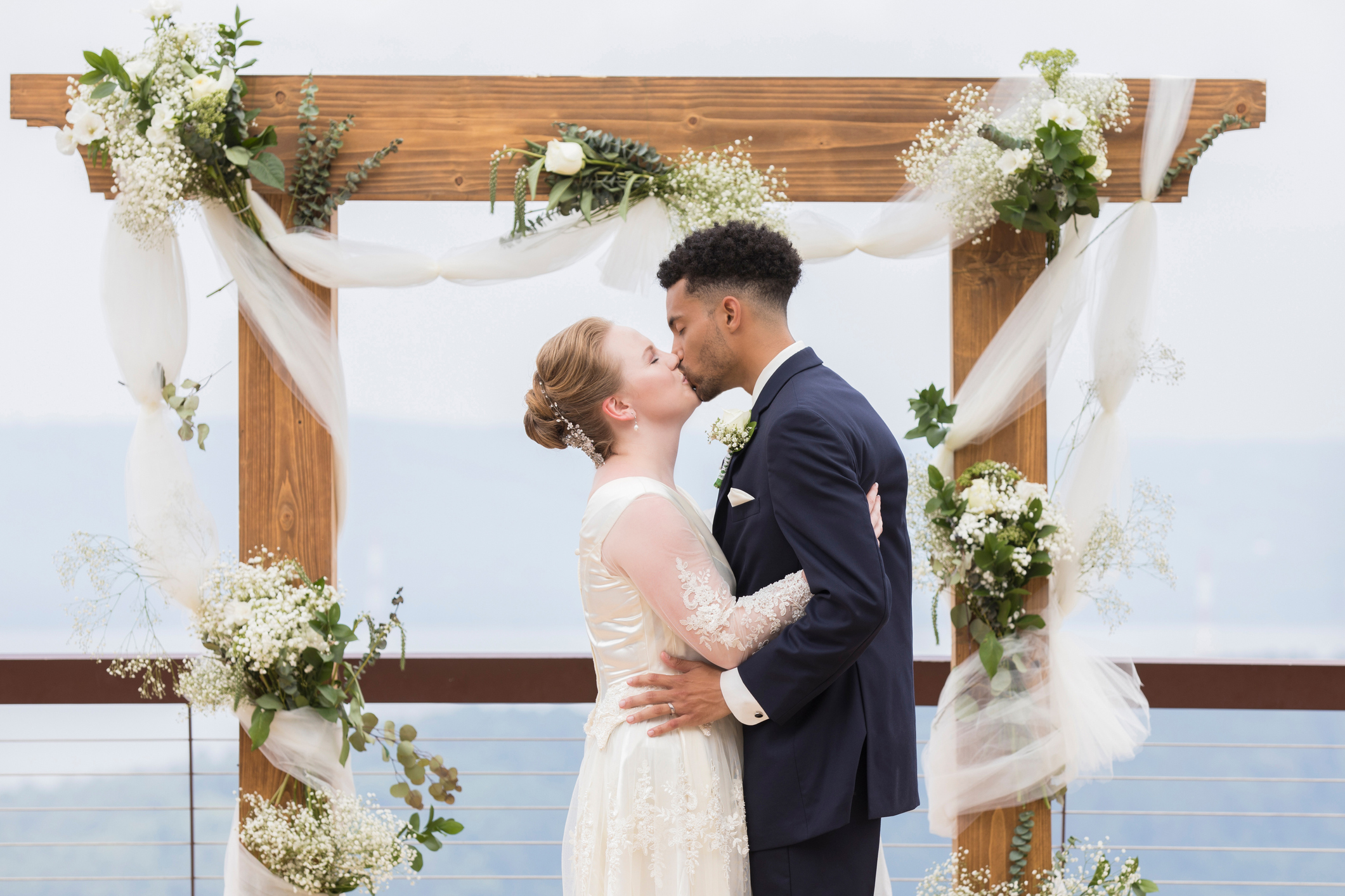 Bride and groom kissing in front of wedding altar backdrop