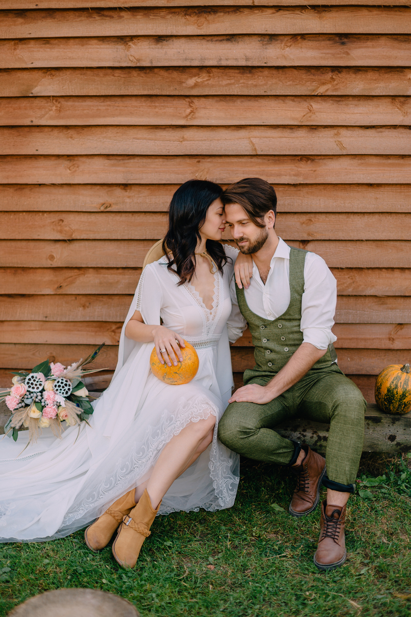 sweet boho style photo, bride wearing cowboy boots and groom wearing suspenders