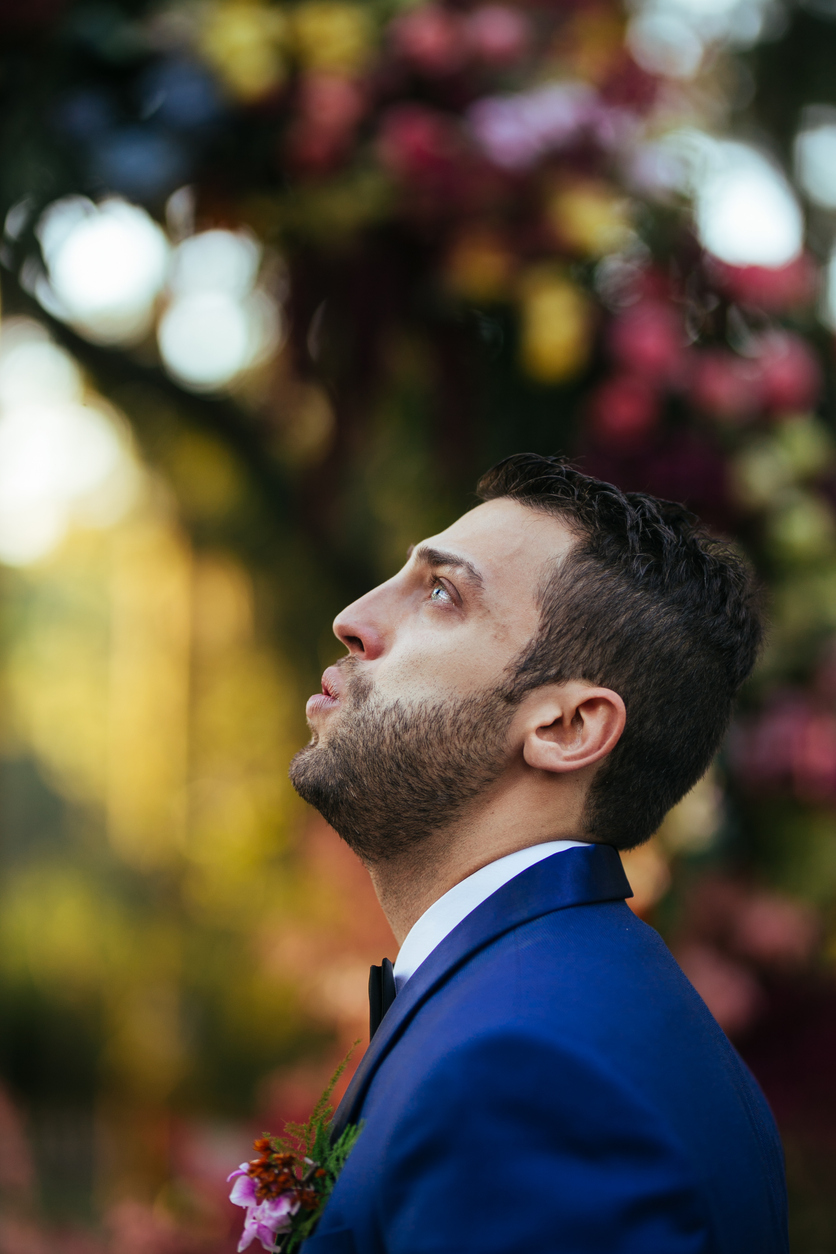 The groom looks up to the sky to keep his tears from falling as a result of his overwhelming emotion upon seeing her bride.