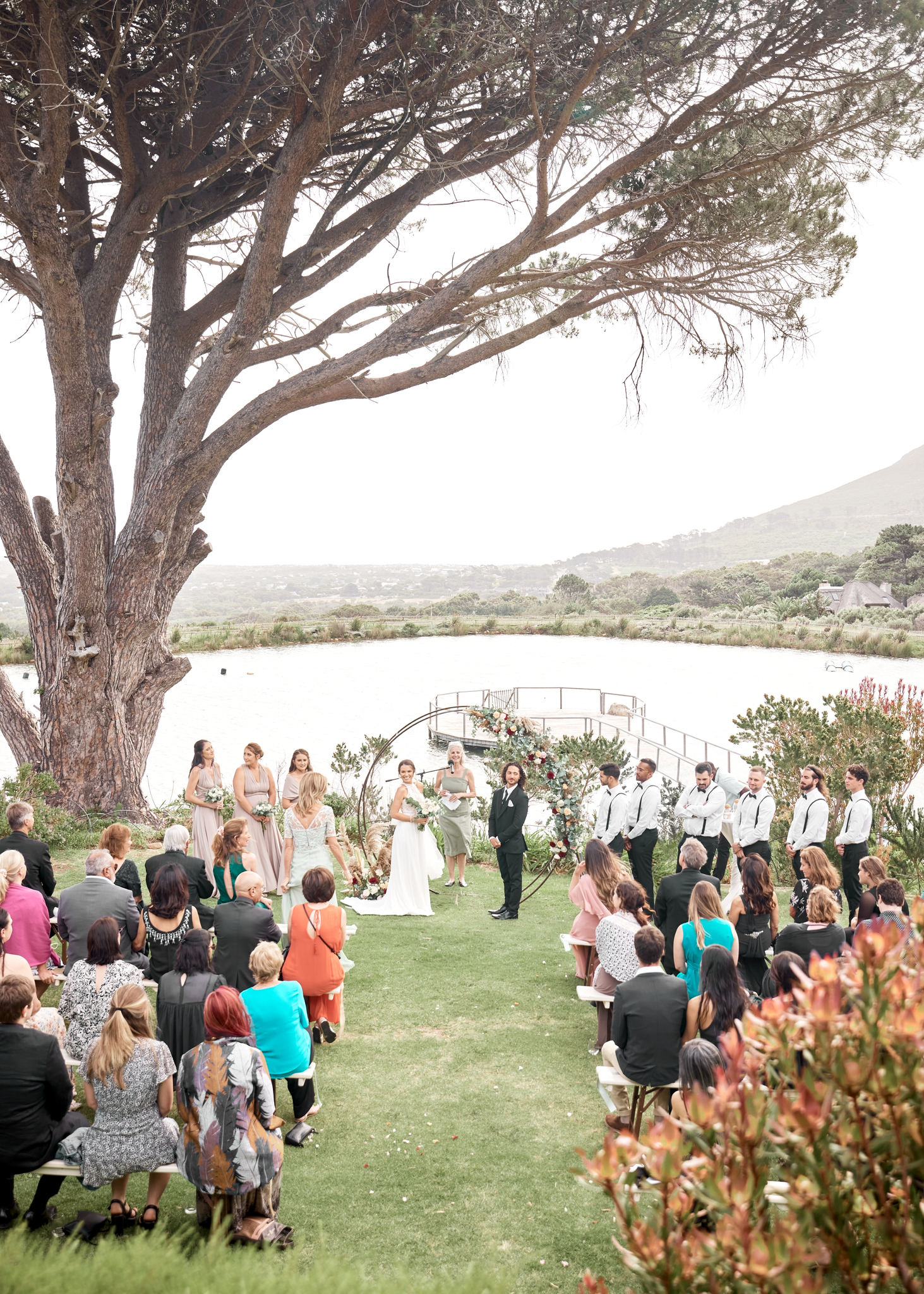 Love, marriage and couple at wedding event or ceremony getting married on a lake nature garden above view. Man and woman partnership, trust and life commitment with group of people, audience or crowd