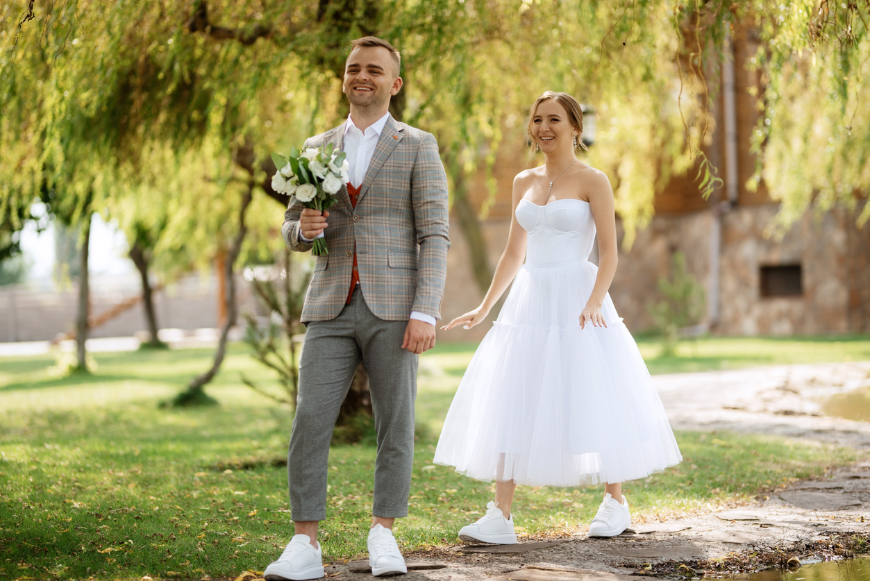 the first meeting of the bride and groom in wedding outfits. The bride in tea-length bridal dress and the groom in gray checkered suit.