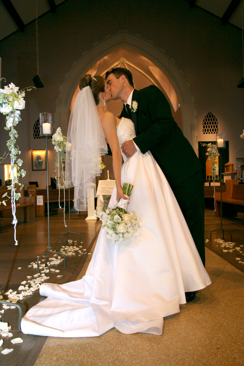 Portrait of a bride and groom inside an old church kissing after ceremony.