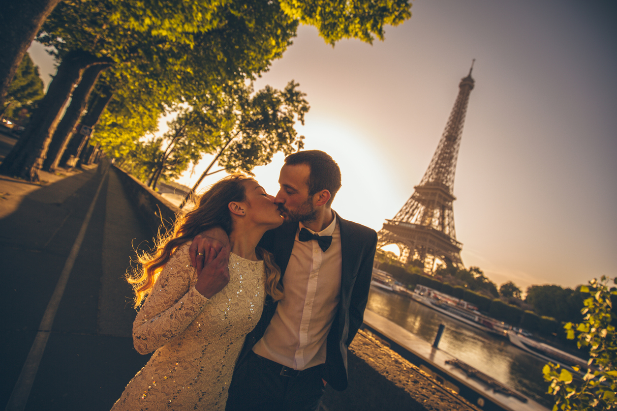 a young married couple beside the river as the sun rises. In the backdrop, you can see the Eiffel Tower.