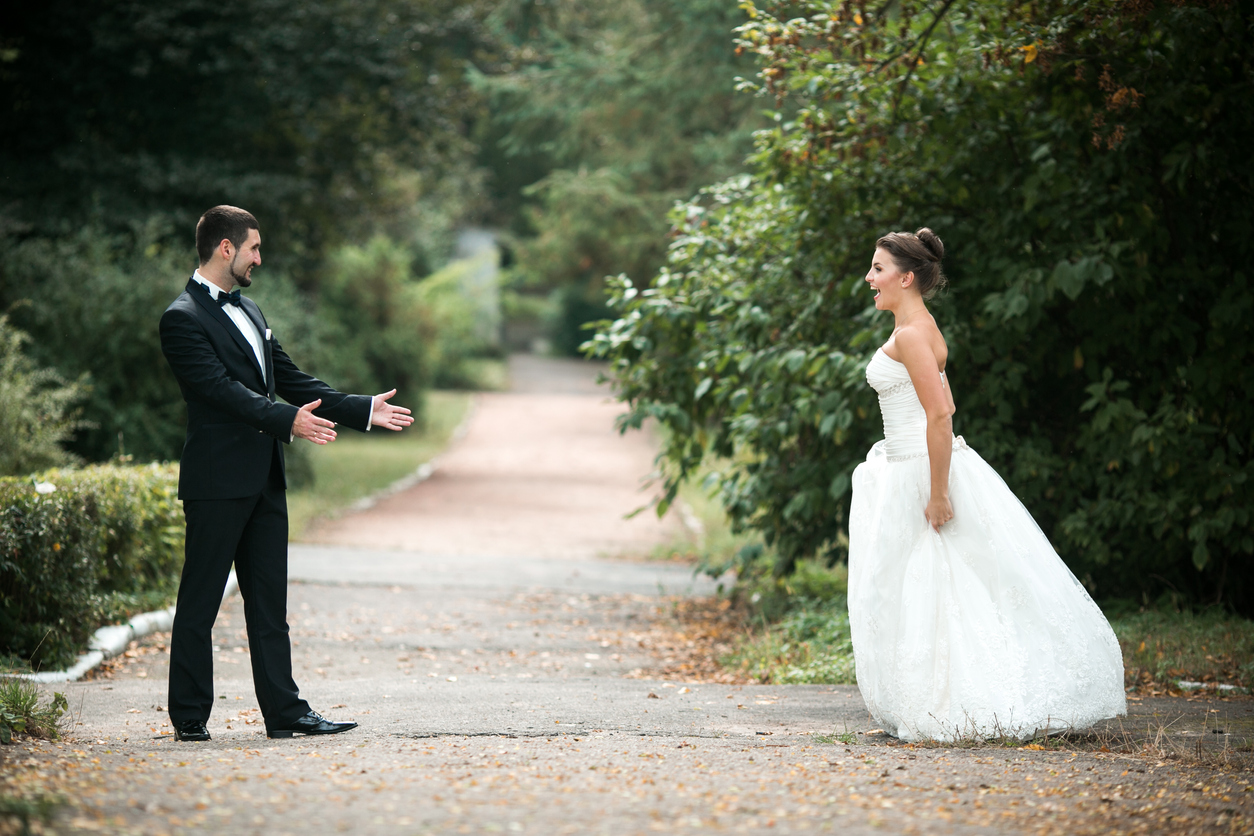 Lovely wedding pair, all smiles, standing opposite one other in the park