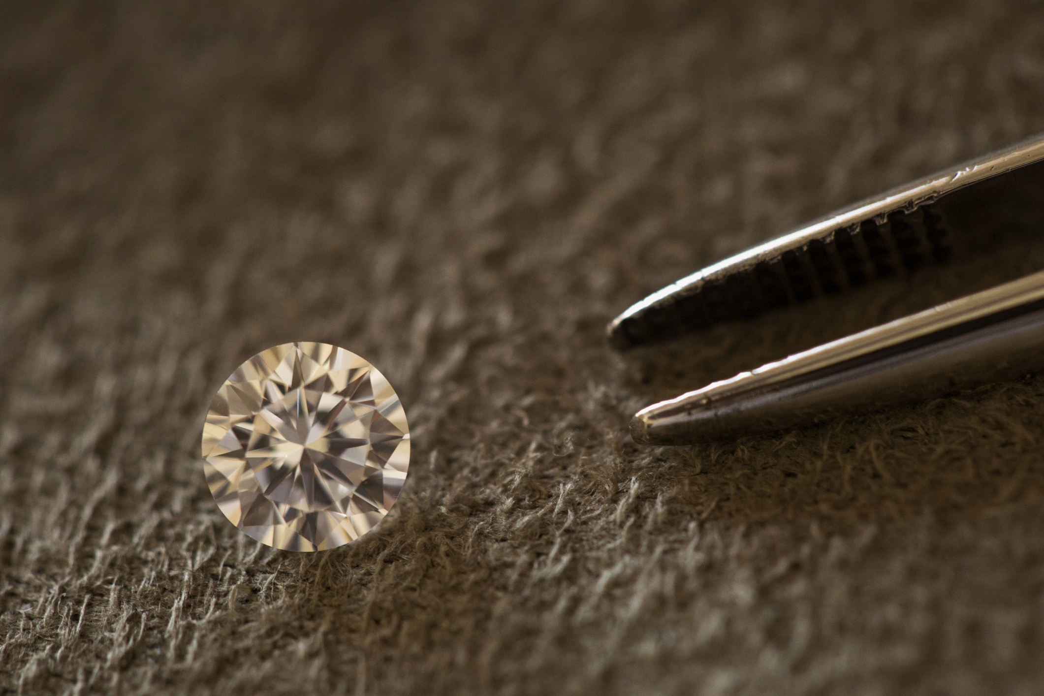 round diamond being inspected with tweezers