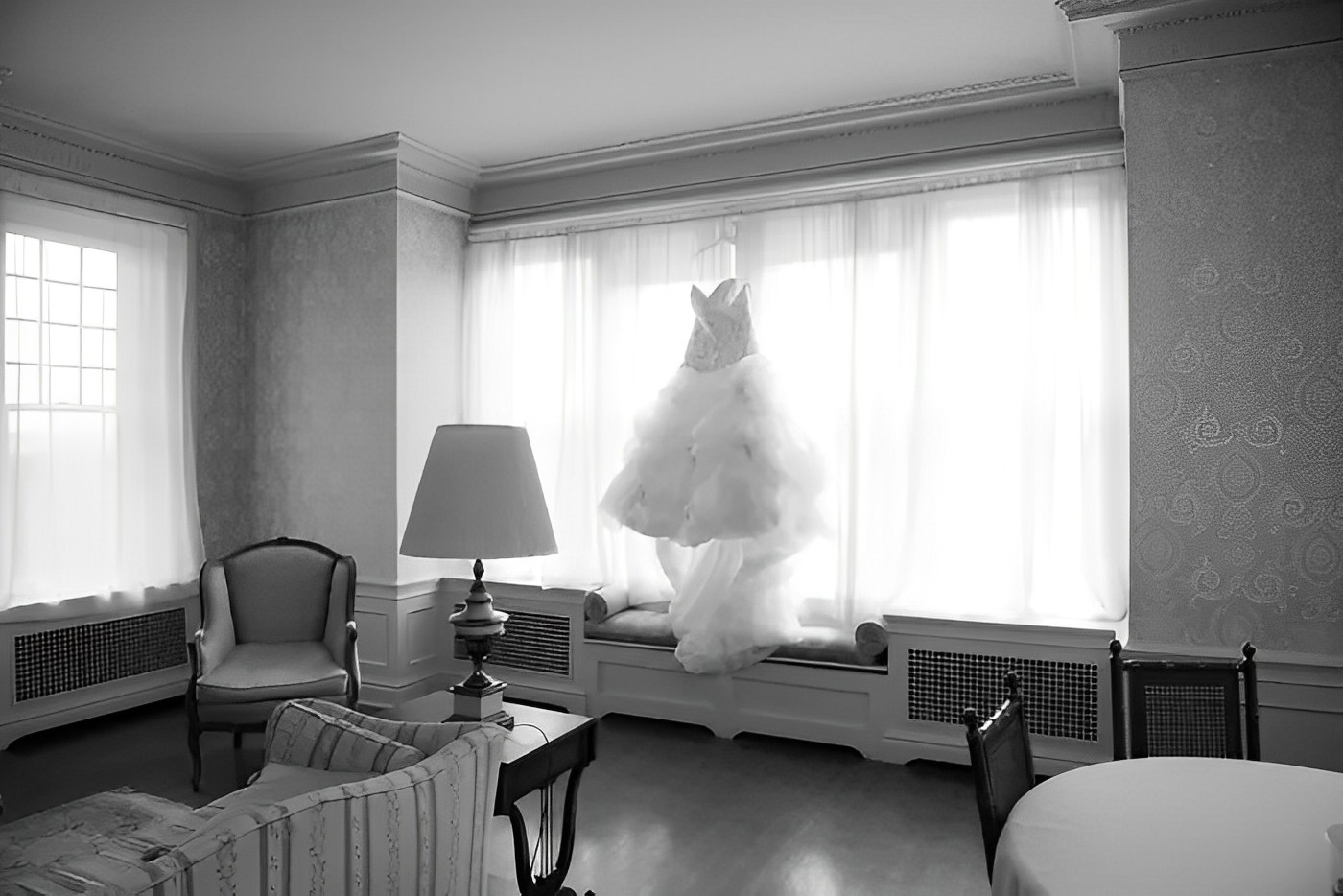 black and white photo of the bride's gown hanged in a window