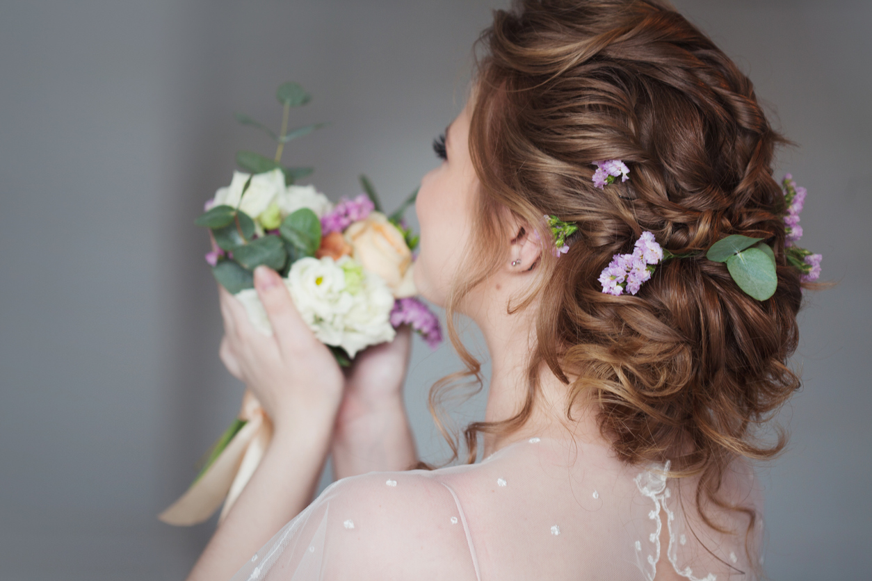 Beautiful and elegant wedding hairstyle. Young bride with bouquet of flowers, back view