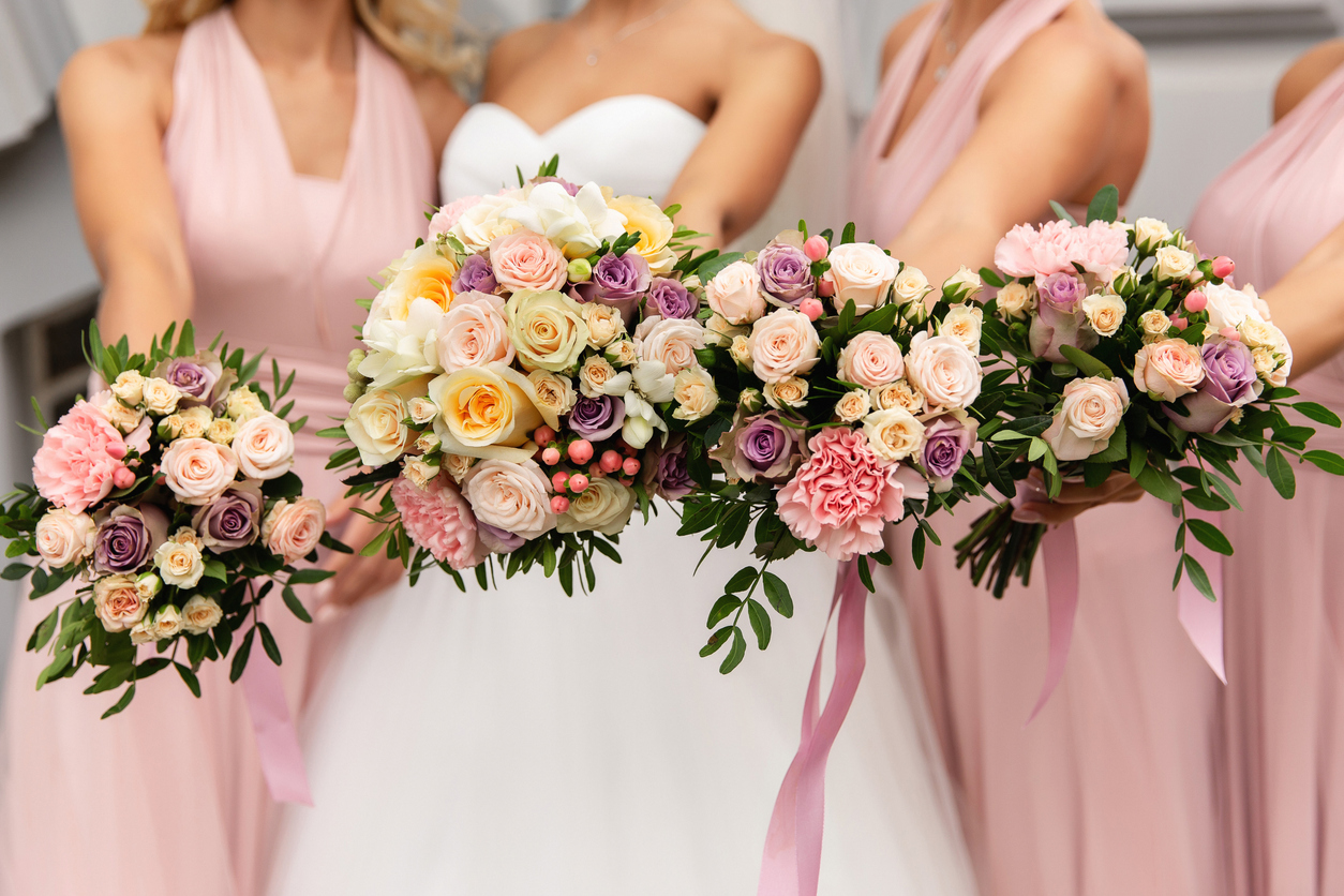 Bride and bridesmaids in pink dresses posing with bouquets at wedding day.