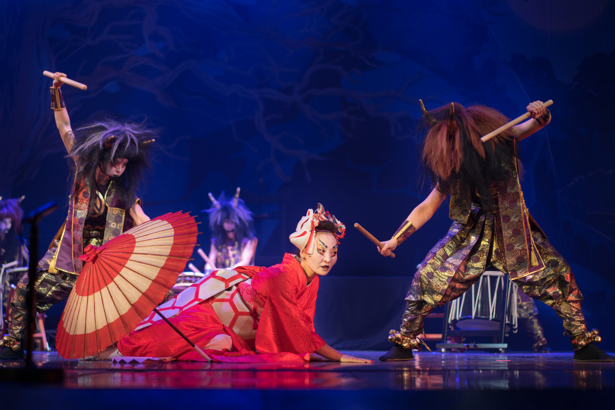 Japanese traditional performance. Demons dance around an actress dressed in a traditional red kimono and wearing a fox mask.