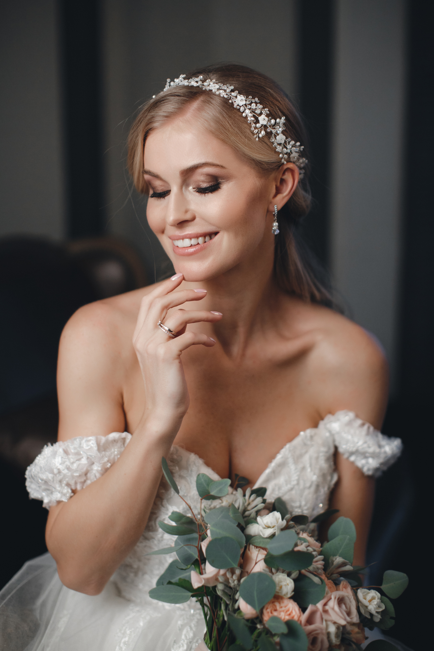 Pretty bride with wedding makeup, fashion jewelry. Beautiful woman posing in white wedding dress. Wedding portrait of happy bride. Bridal fashion model posing in interior. Gorgeous beauty, young bride