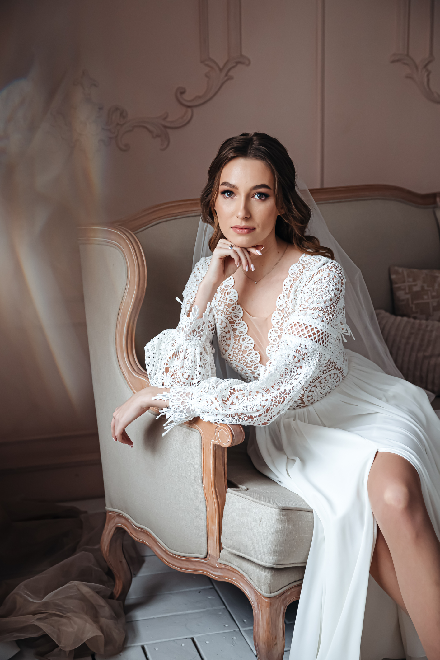 Pensive bride posing in an armchair in a boho style wedding dress. Wedding photo session, bride's morning.