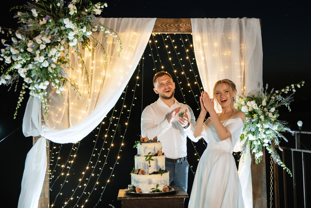 An evening wedding would benefit from this stunning DIY background of white fabric and glittering lights, which adds romance and sophistication.