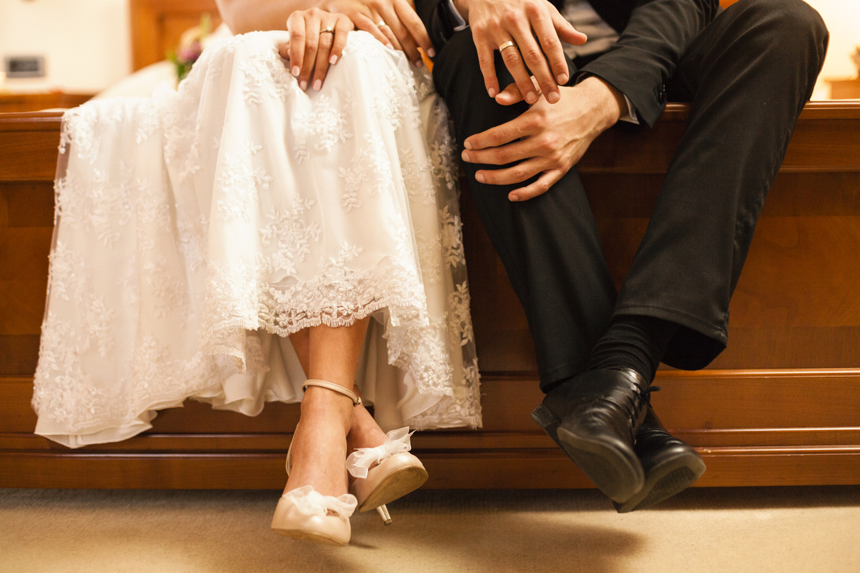 a lower angle on bride and husband seated while accentuating their wedding jewelry.