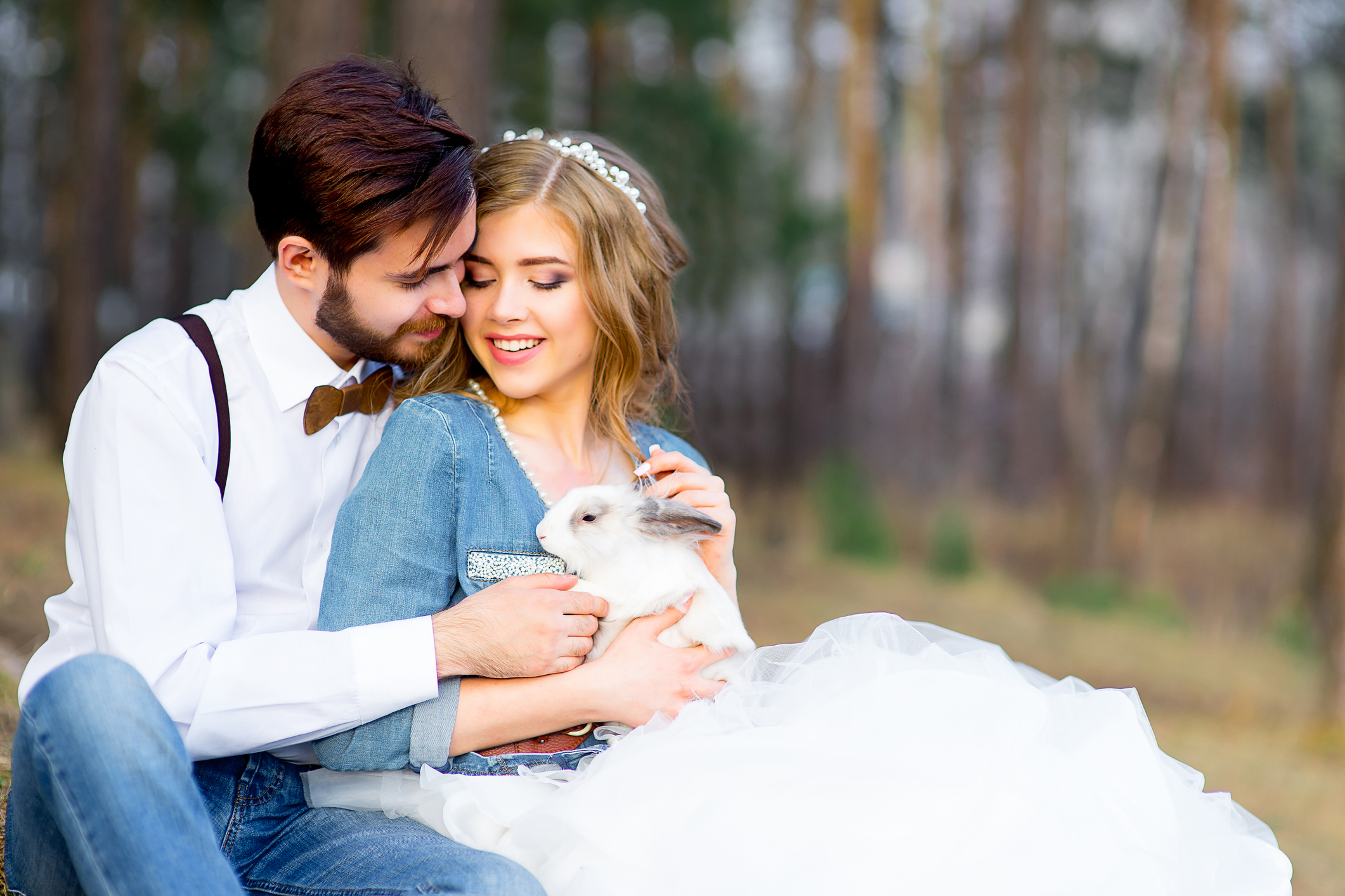 wedding, country-style glamor in the forest. Newlyweds posing among pine trees with white fluffy rabbits