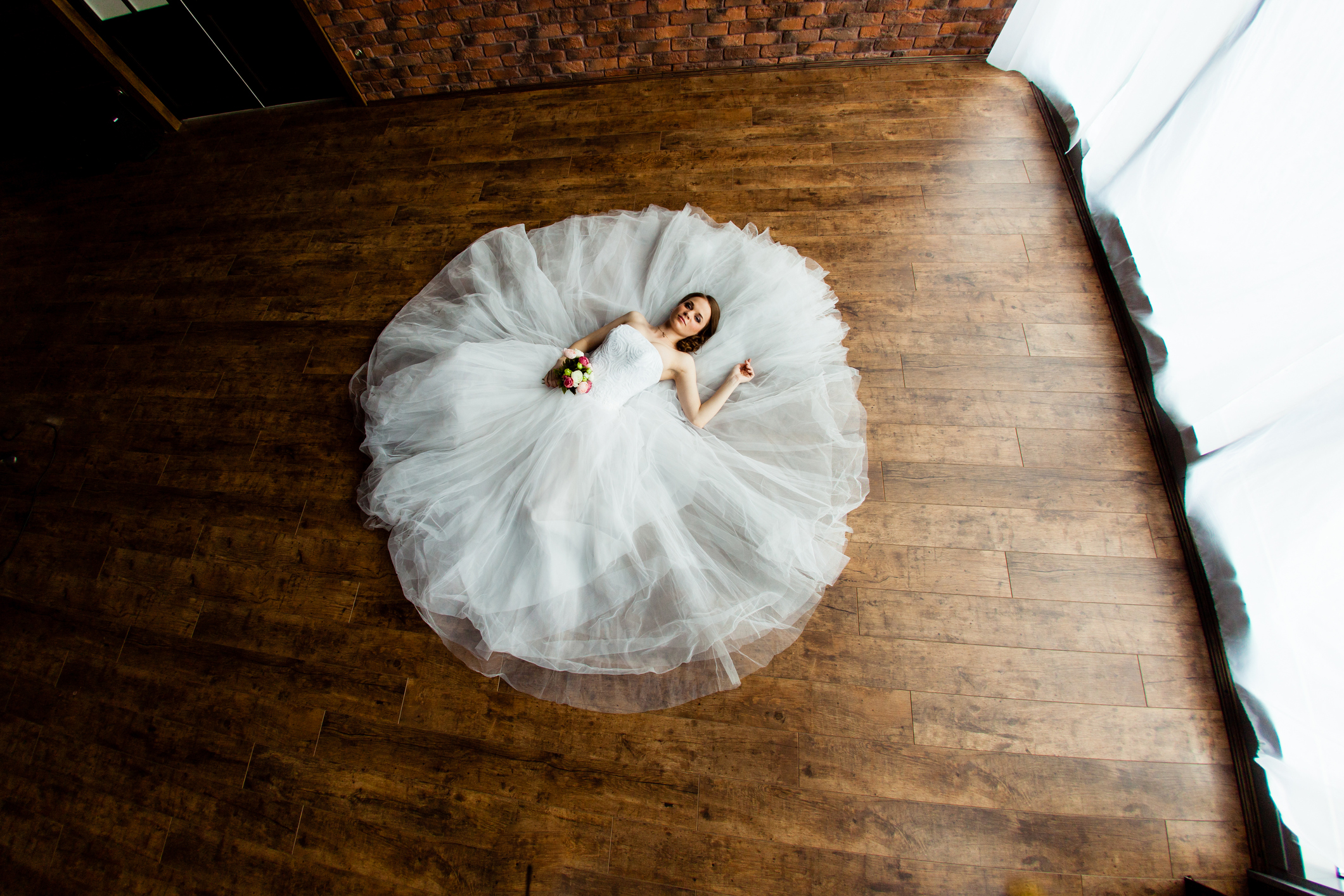 Young sexy bride in the studio is lying on the wooden floor