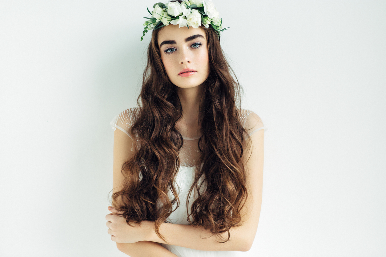 simple wedding hairstyle of the bride with flowing wavy hair and flower crown on hear head.