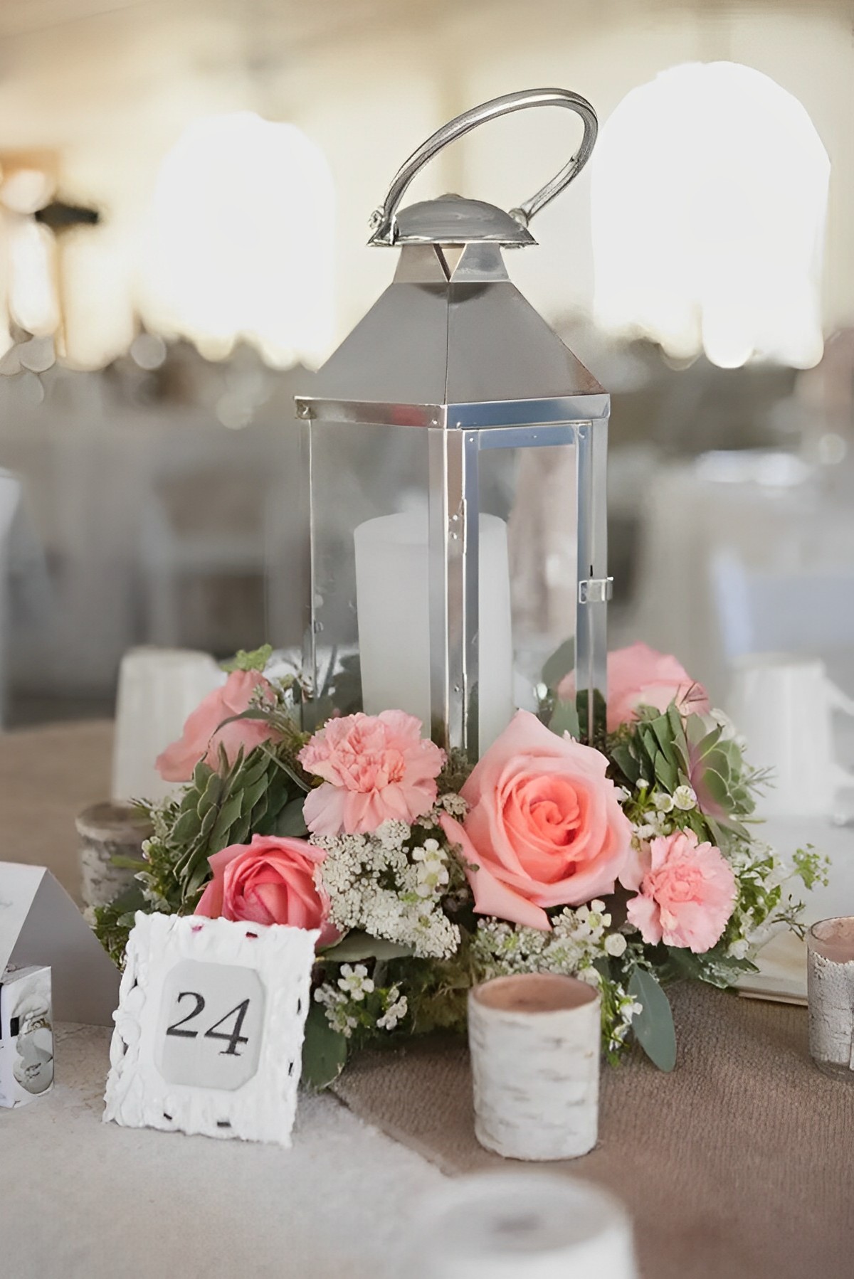 The silver lantern adorned with delicate pink roses and fragile baby's breath is a picture of beauty. The lovely mix of pink roses and baby's breath oozes innocence and purity, making it a suitable decorative item for weddings.