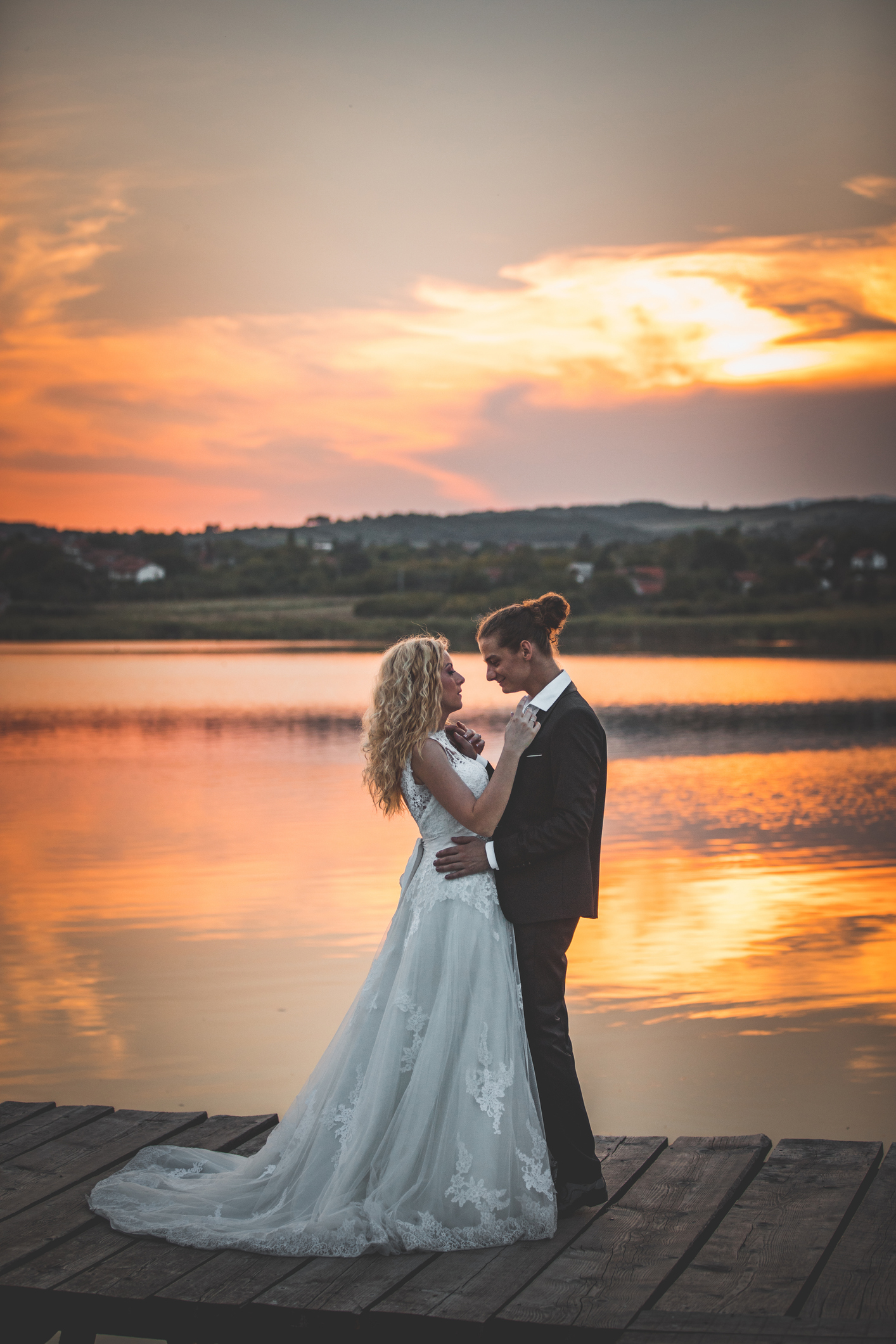 Happy newlywed couple dancing on like pier at sunset