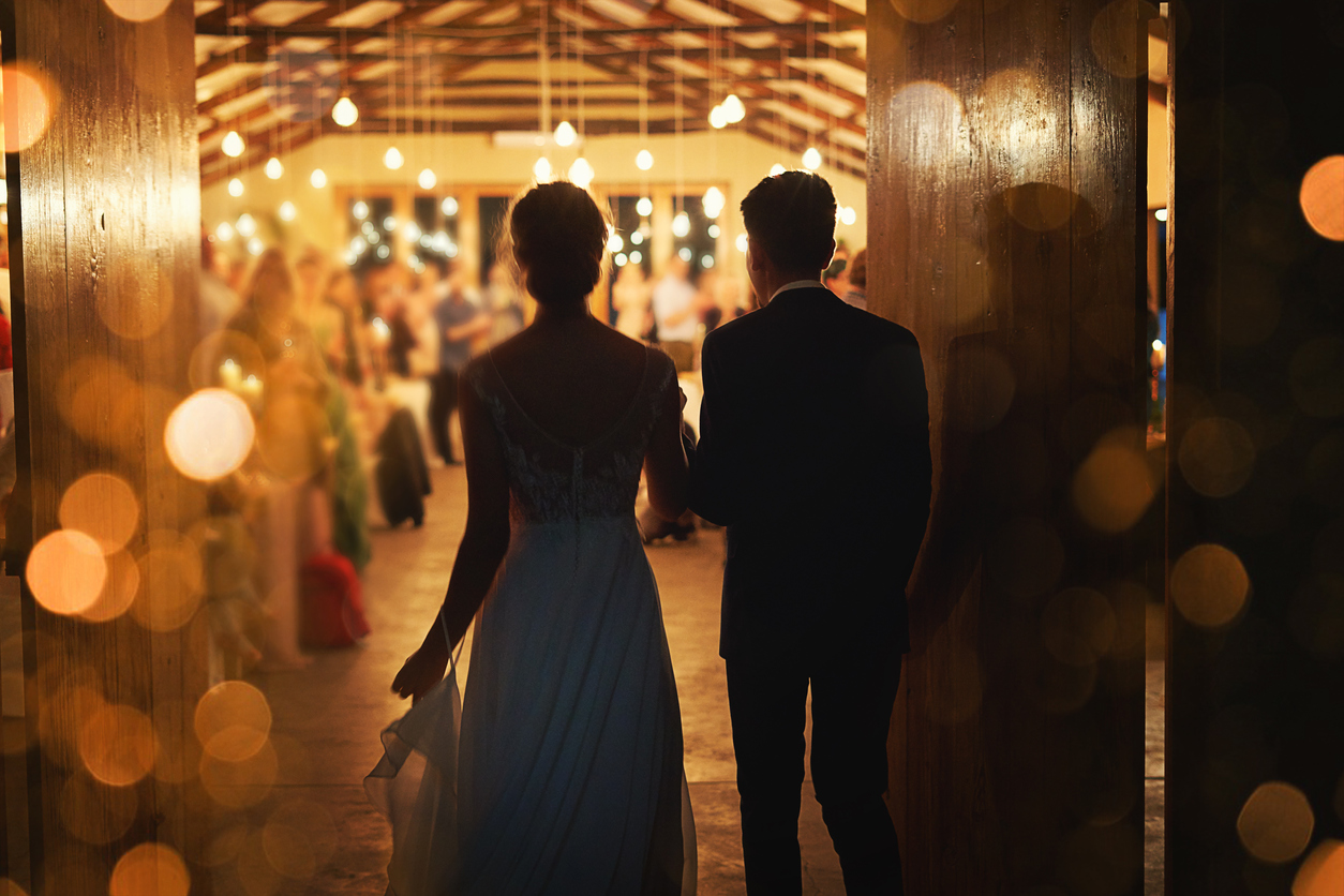 Rearview shot of a young couple arriving hand in hand making a grand entrance at their wedding reception.