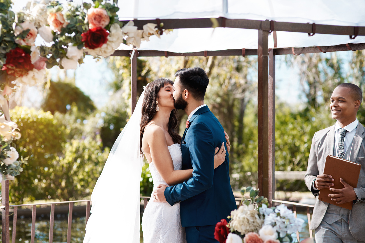 On their wedding day, a loving young couple kisses while standing at the altar, and this kiss verifies their vows.