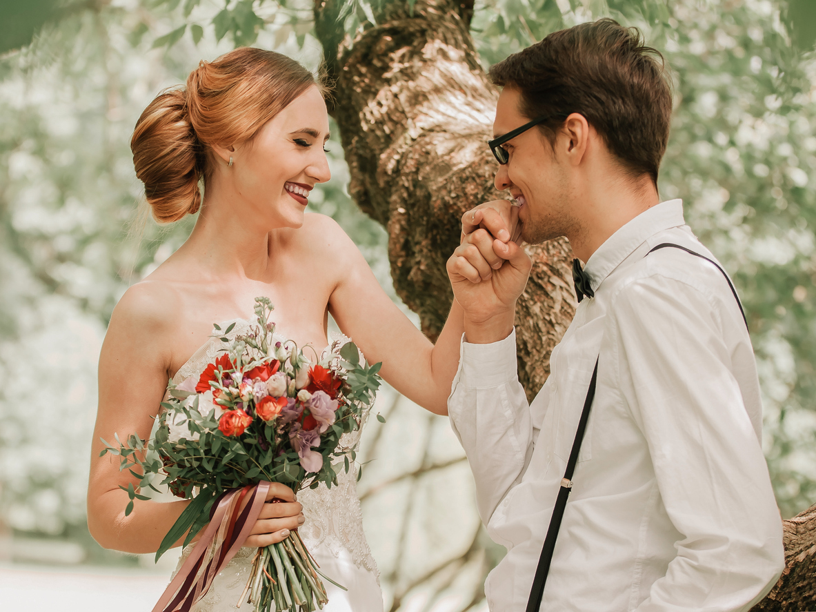 the joyful groom is seen planting a kiss on his bride's hand as they walk together, creating a romantic moment.