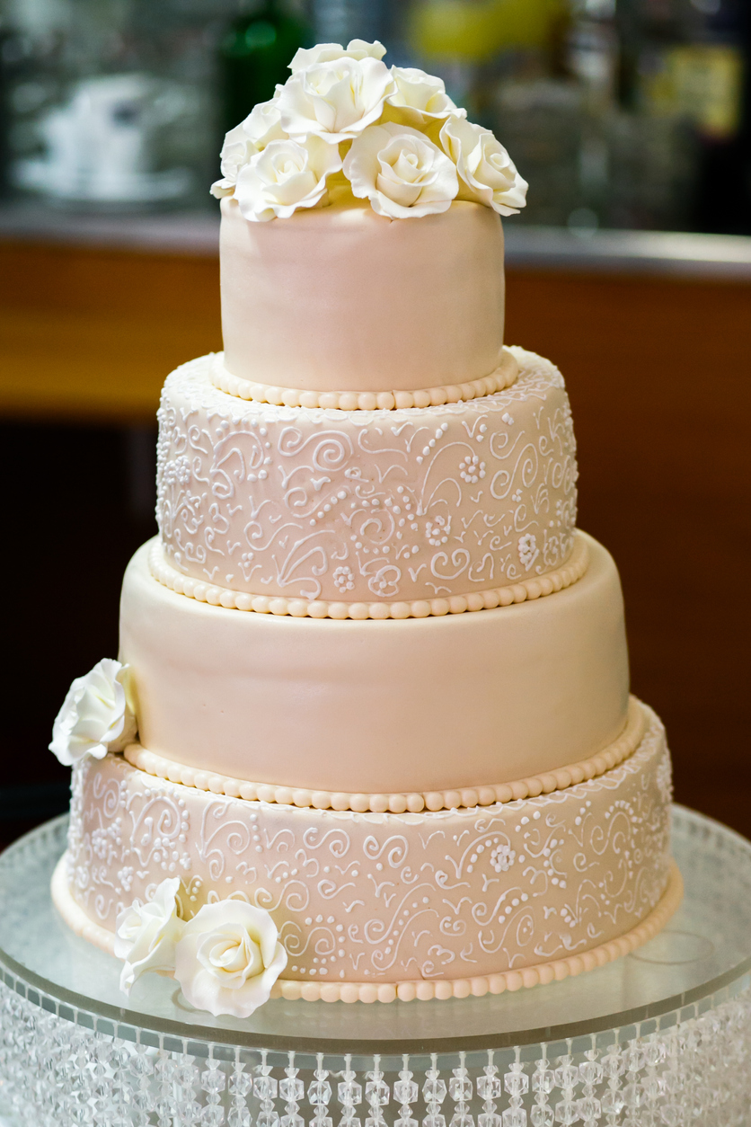 a peach-colored four-layer cake with a simple and lovely pattern with roses.