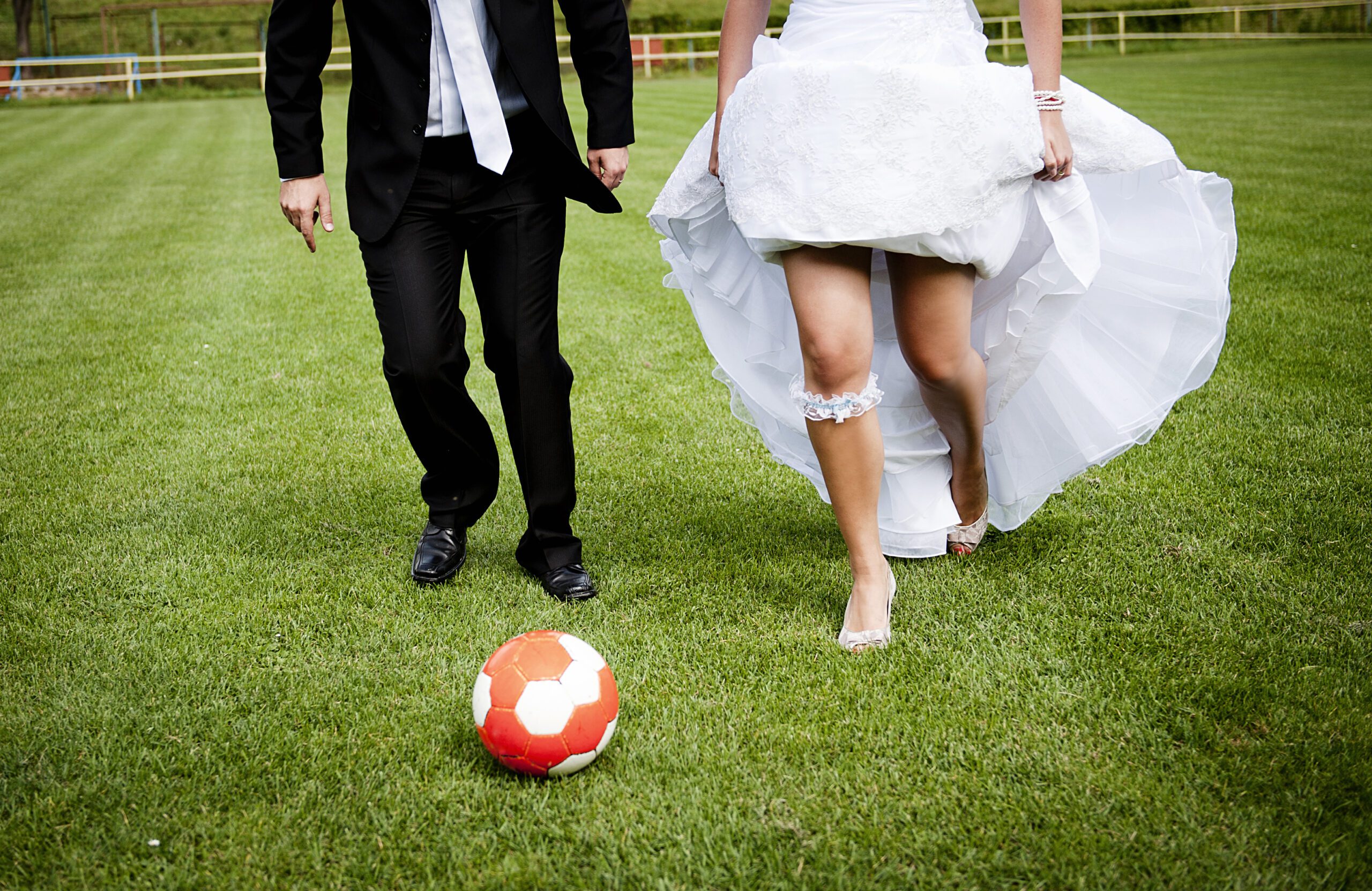 lower half body shot of the bride and groom playing on the football pitch