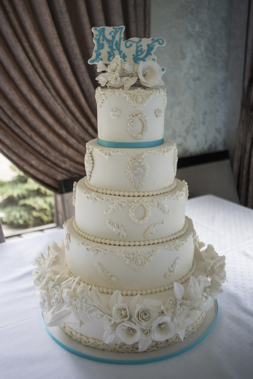 MK letter topper and floral decoration on a five-tier luxury wedding cake.