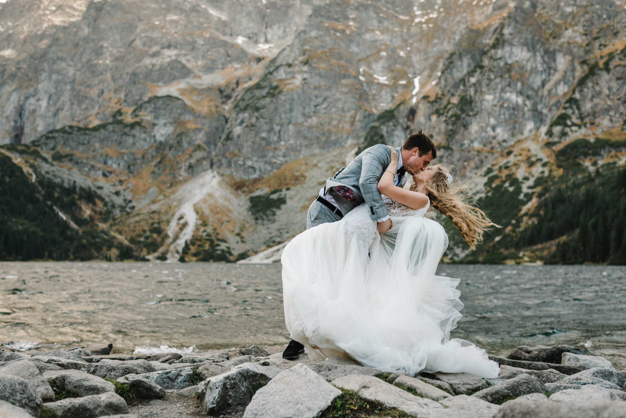 The bride and groom near the lake in the mountains. A couple together against the backdrop of a mountain landscape. Morskie Oko (Sea Eye) Lake. Tatra mountains in Poland.