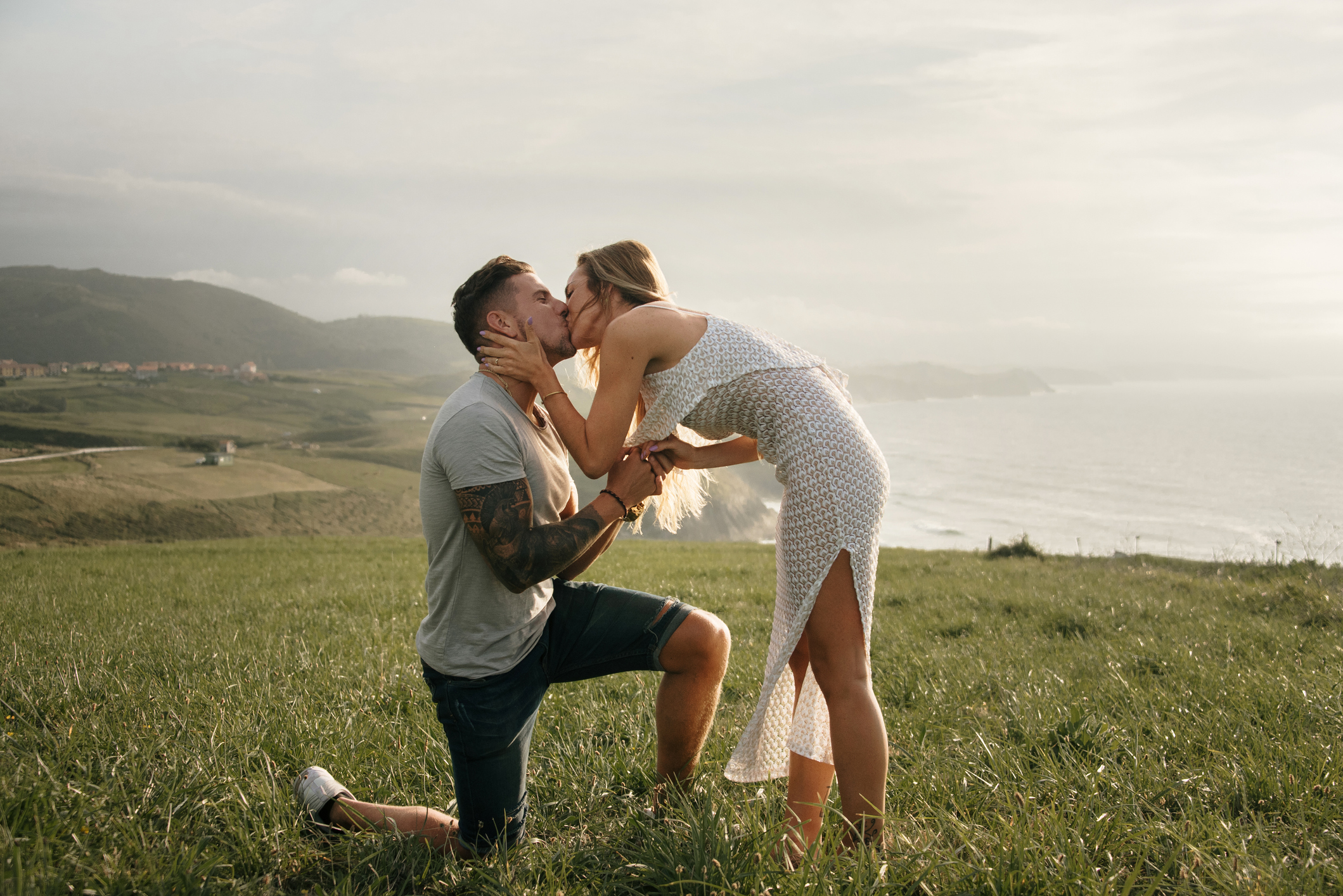 Young man kneeeling, proposing to his girlfriend by the sea