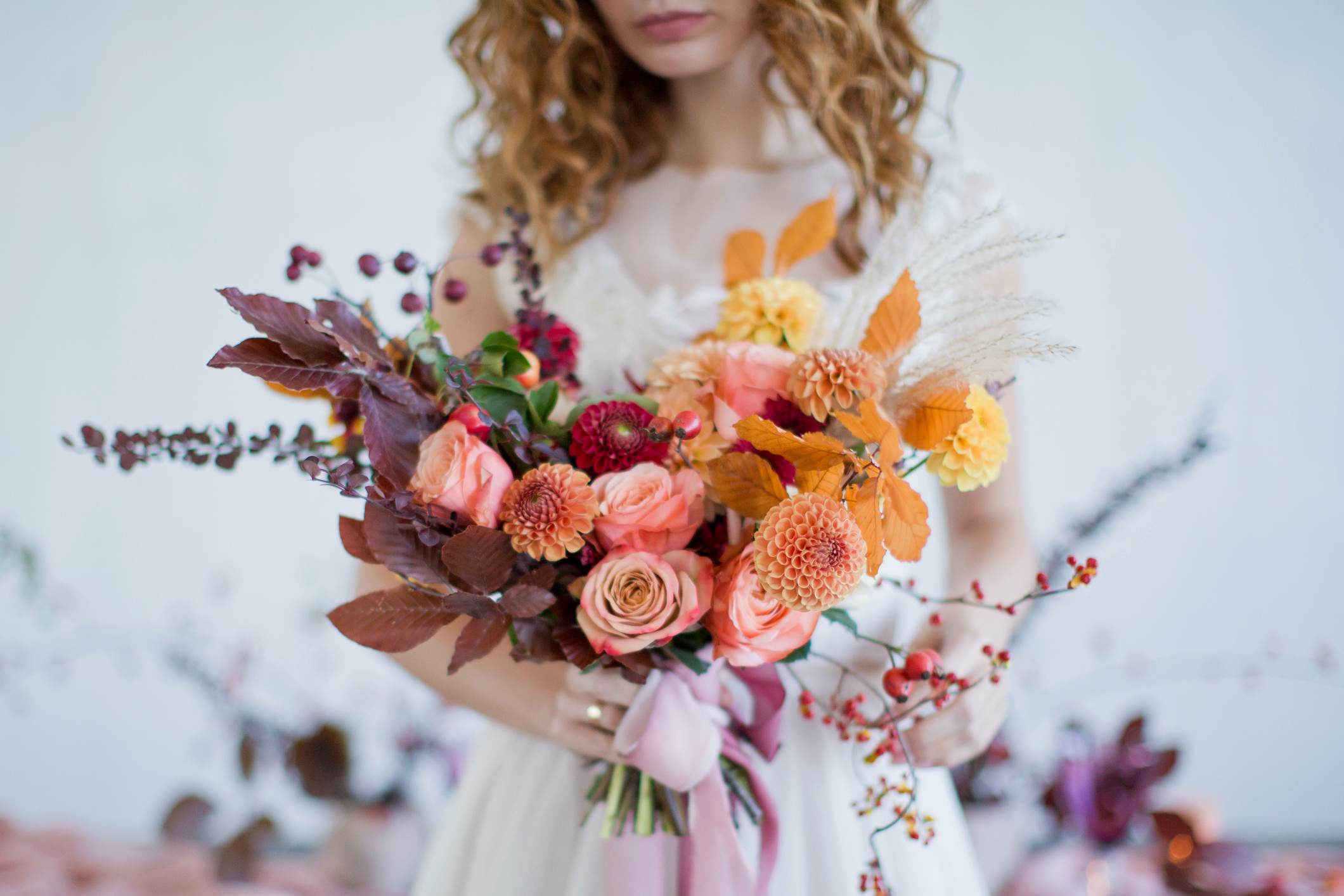 bride holds beautiful autumn bouquet with orange and red flowers, roses and berries