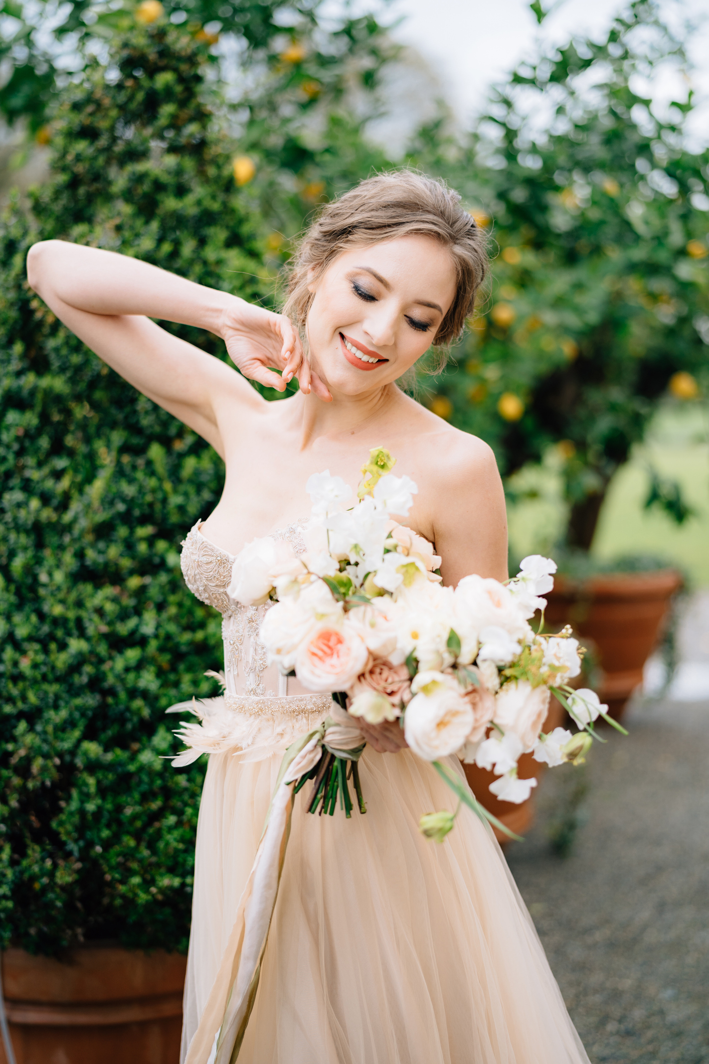 Smiling bride in a beautiful dress with a bouquet of flowers on a background of a green tree in a tub. Lake Como. High quality photo