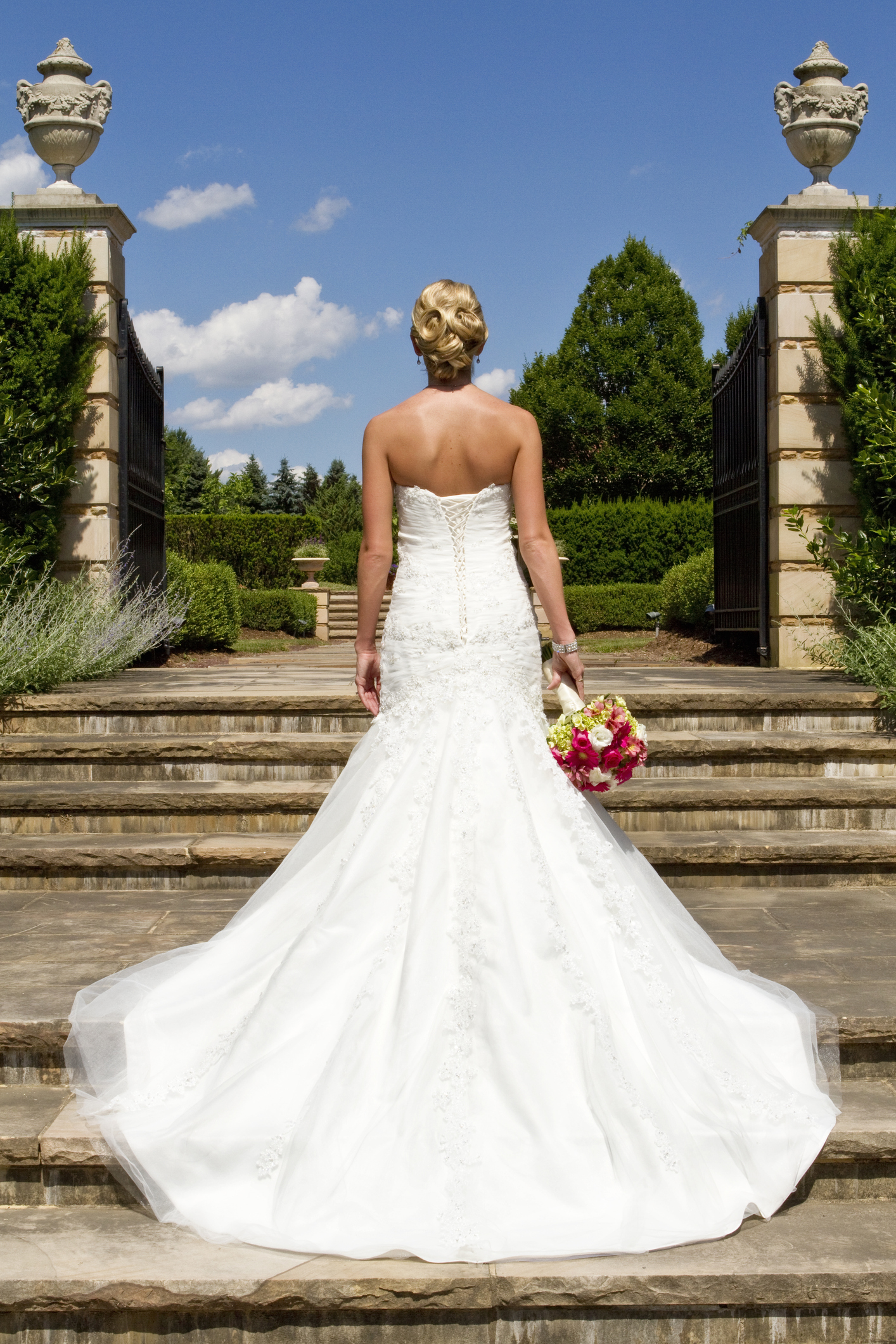 back view photo of beautiful bride standing on steps to the garden