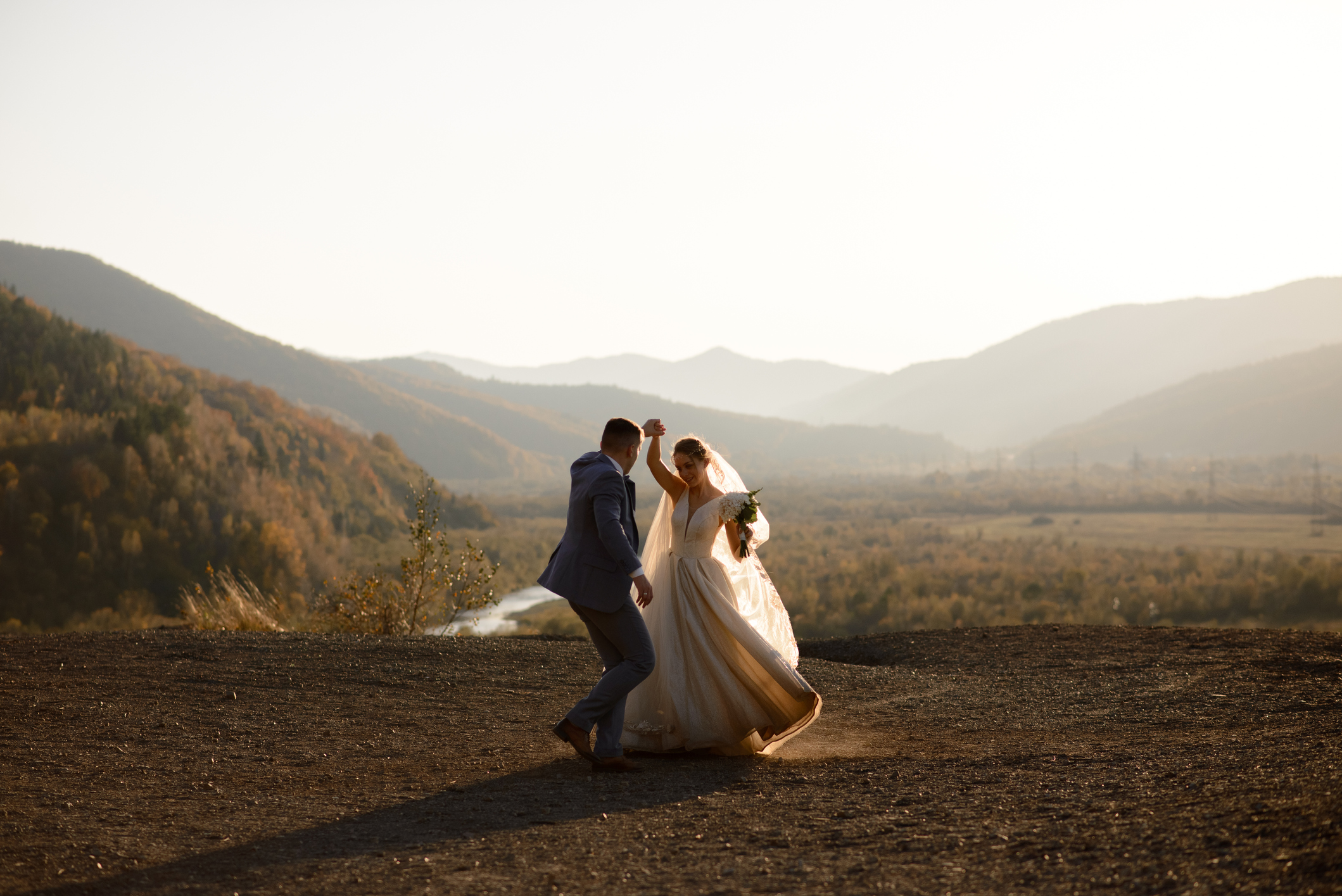 Wedding photo session of the bride and groom dancing in the mountains. Photoshoot at sunset.