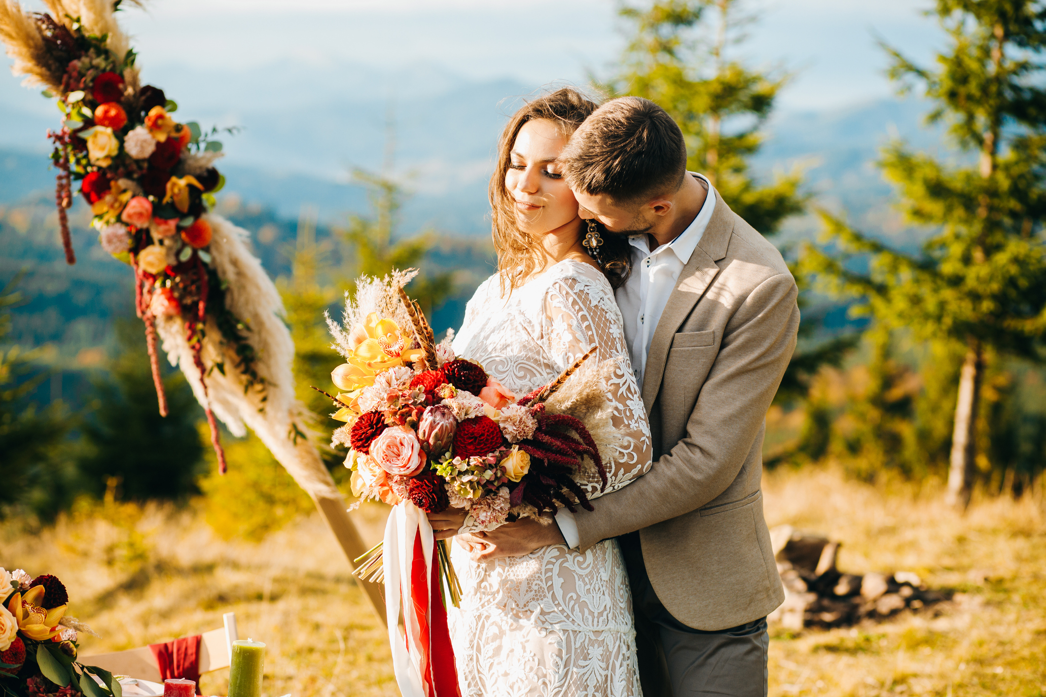 Happy couple hugging under wedding arch. Fall wedding theme.